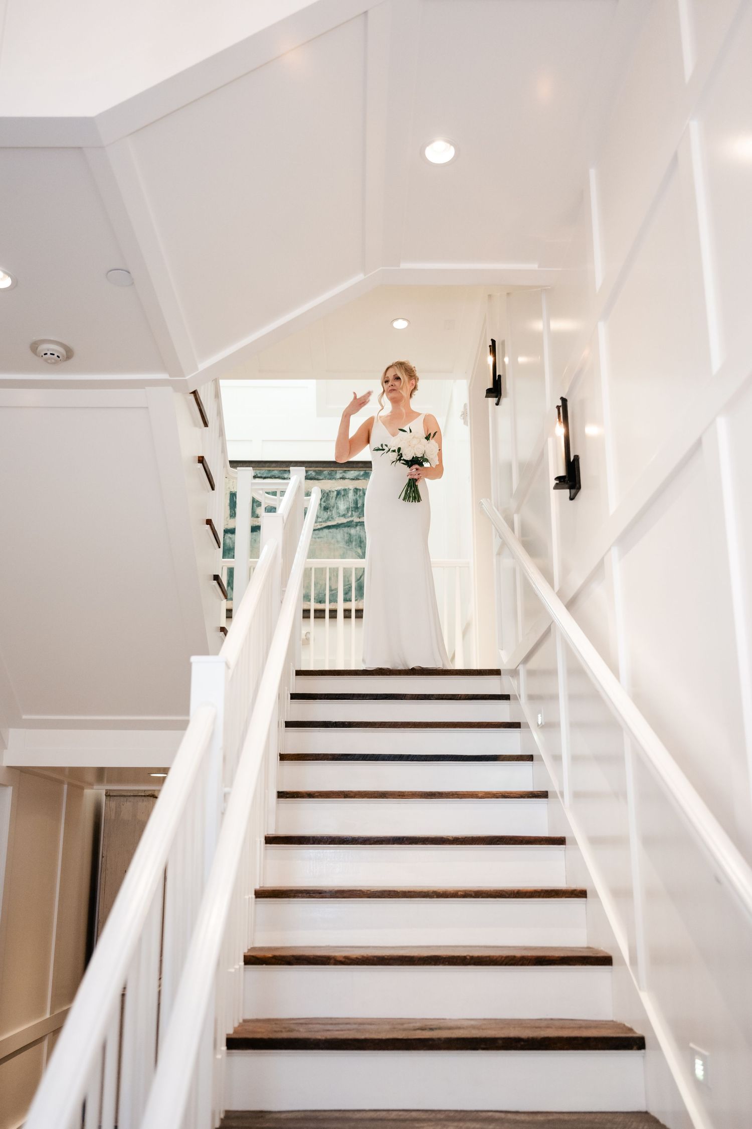 White staircase with dark wood steps and white railings in a bright modern interior.