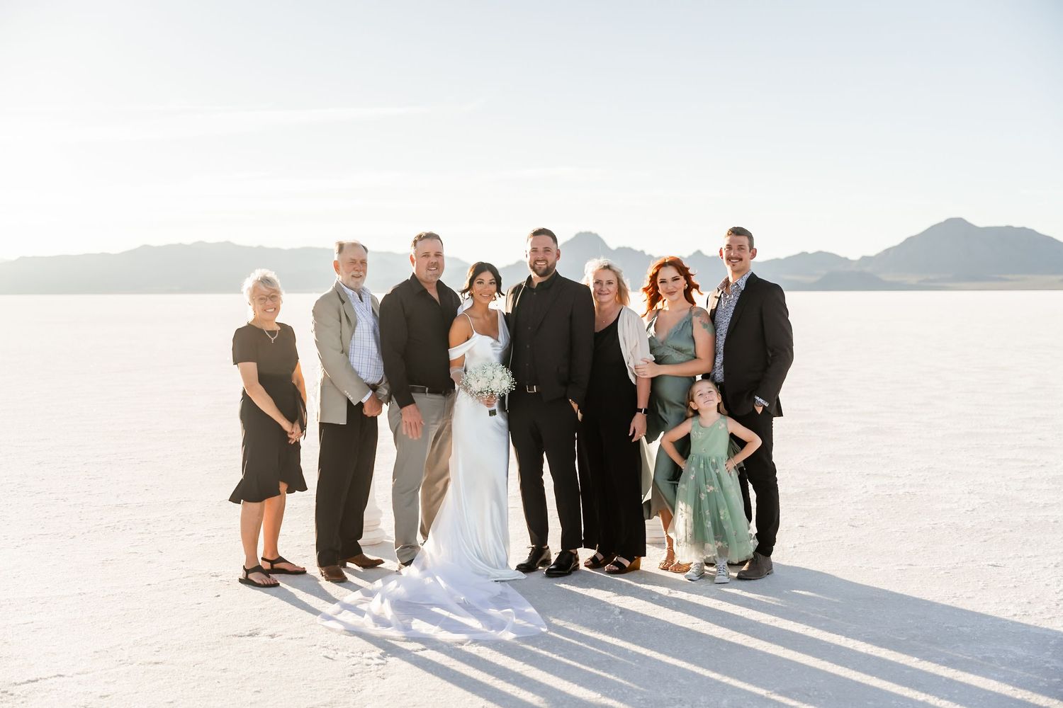 Wedding party group photo on salt flats with mountain backdrop.