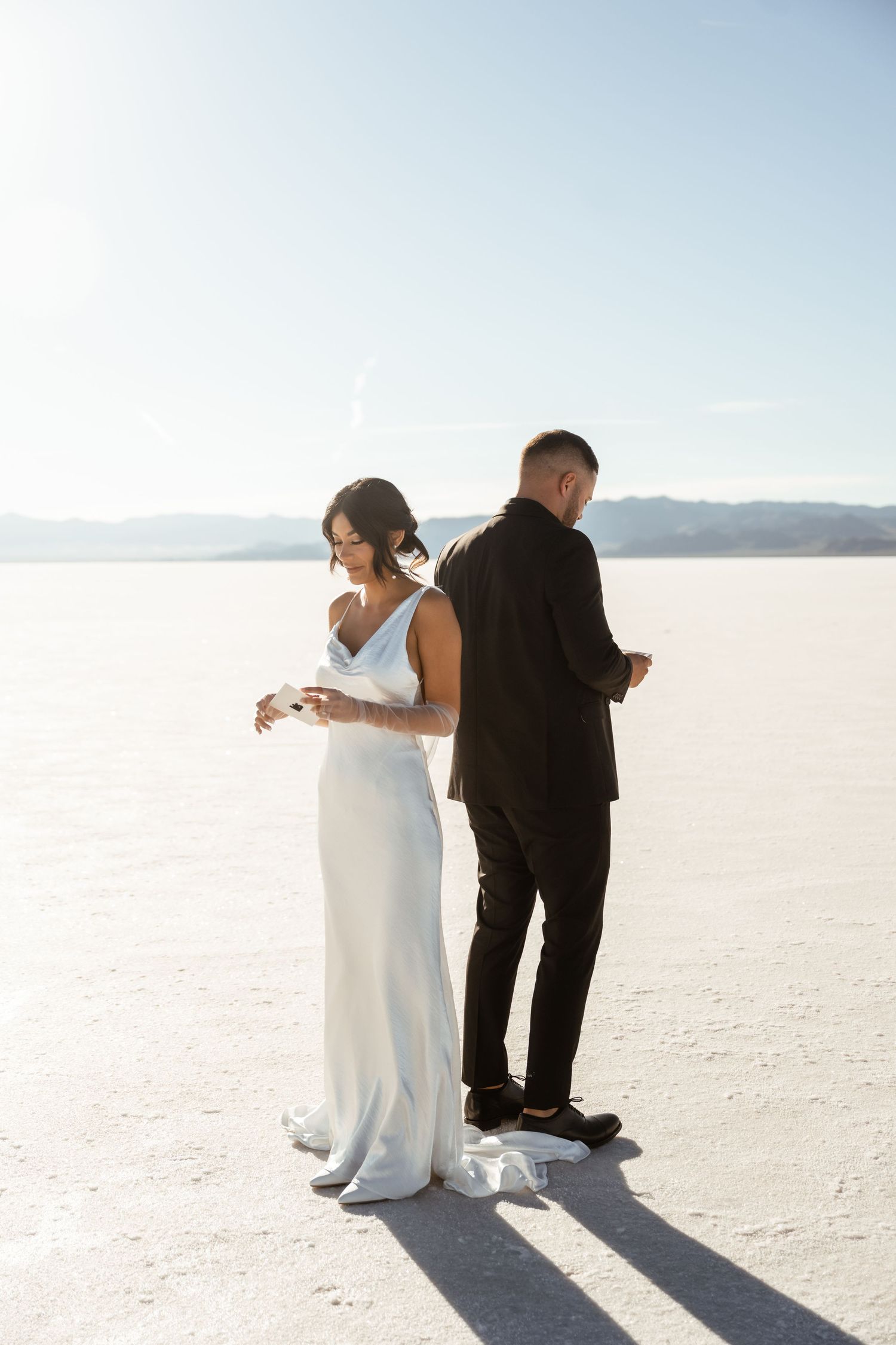 Wedding couple poses artistically on salt flats with dramatic white landscape.