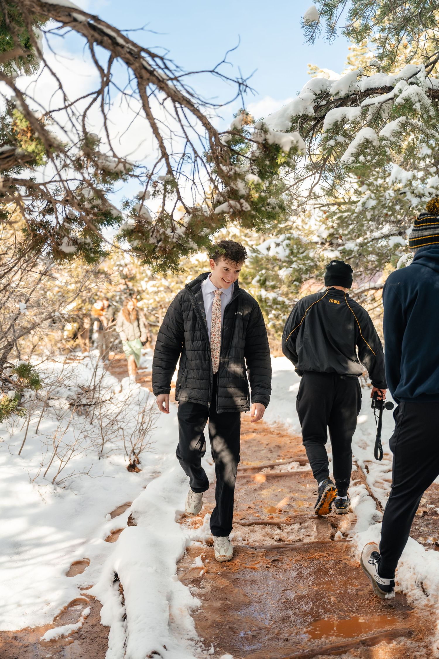 Group walking along a snowy hiking path through winter landscape.