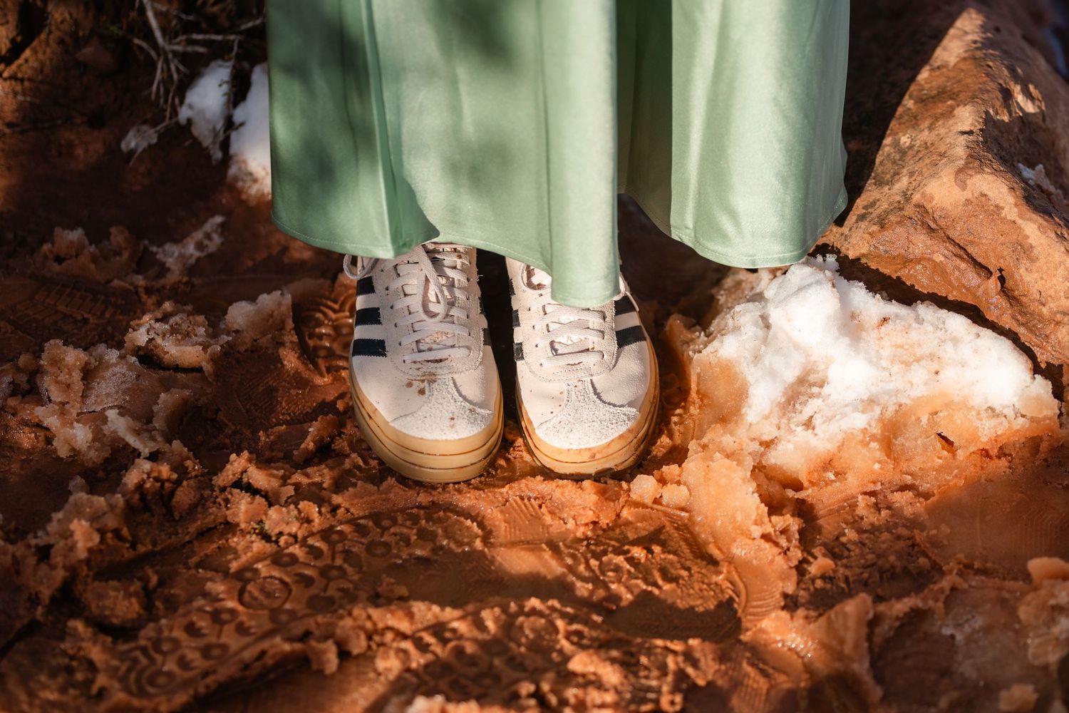 Mint green pants and sneakers standing on red desert rock surface.