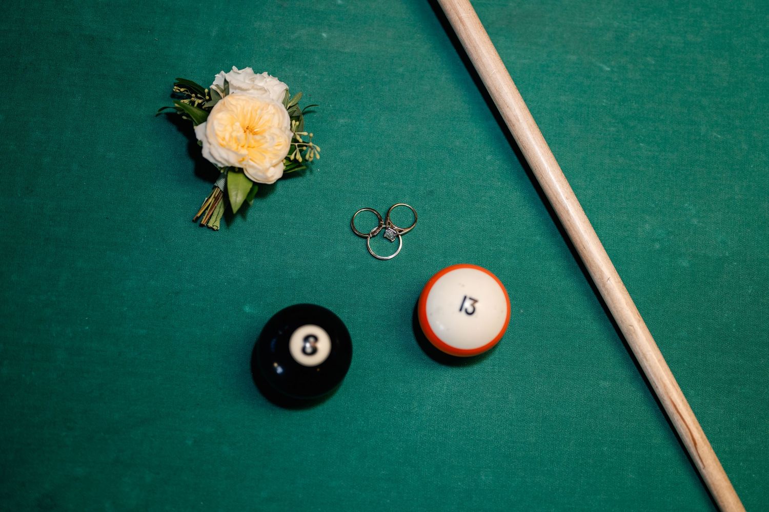 Pool table close-up showing billiard balls and cue stick on green felt surface.