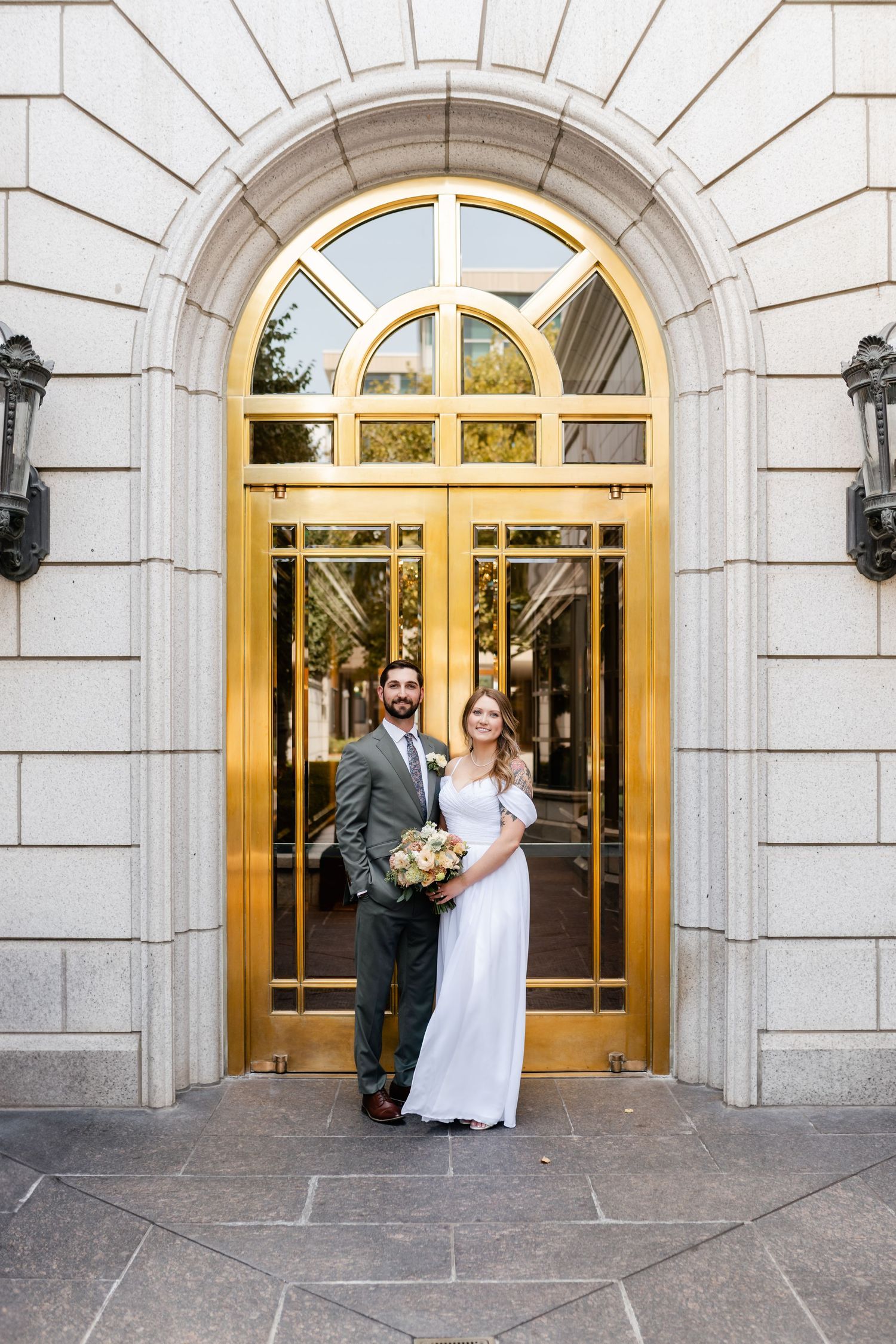 Wedding portraits captured in front of ornate golden doorways at historic building entrance.