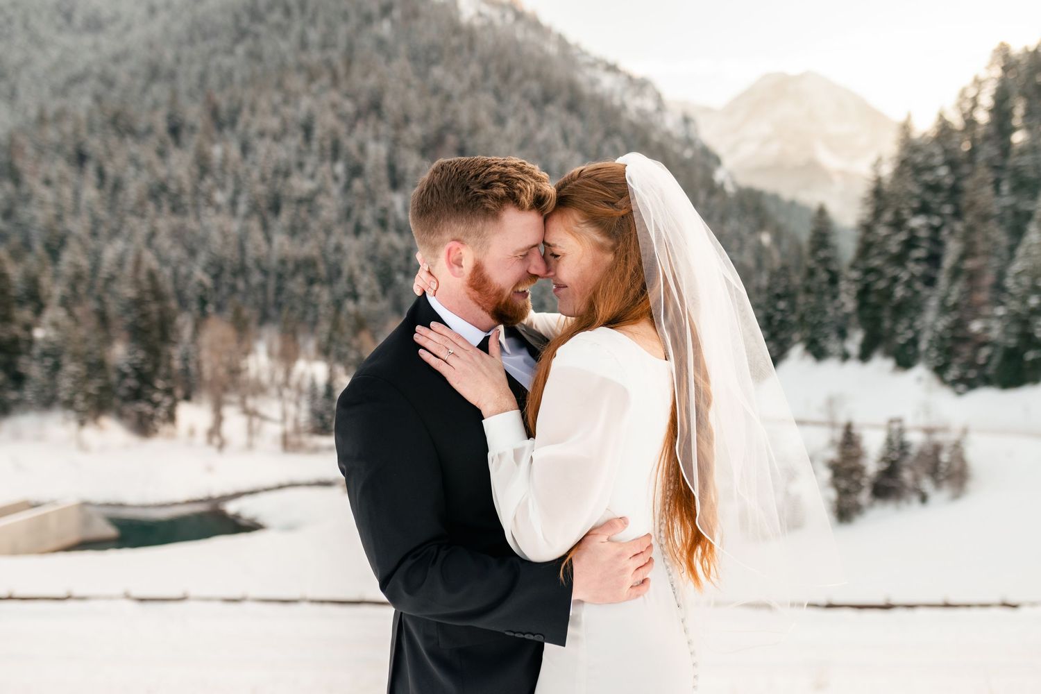 A romantic winter wedding photoshoot in a snow-covered mountain landscape with evergreen trees in the background. LDS wedding Photographer.