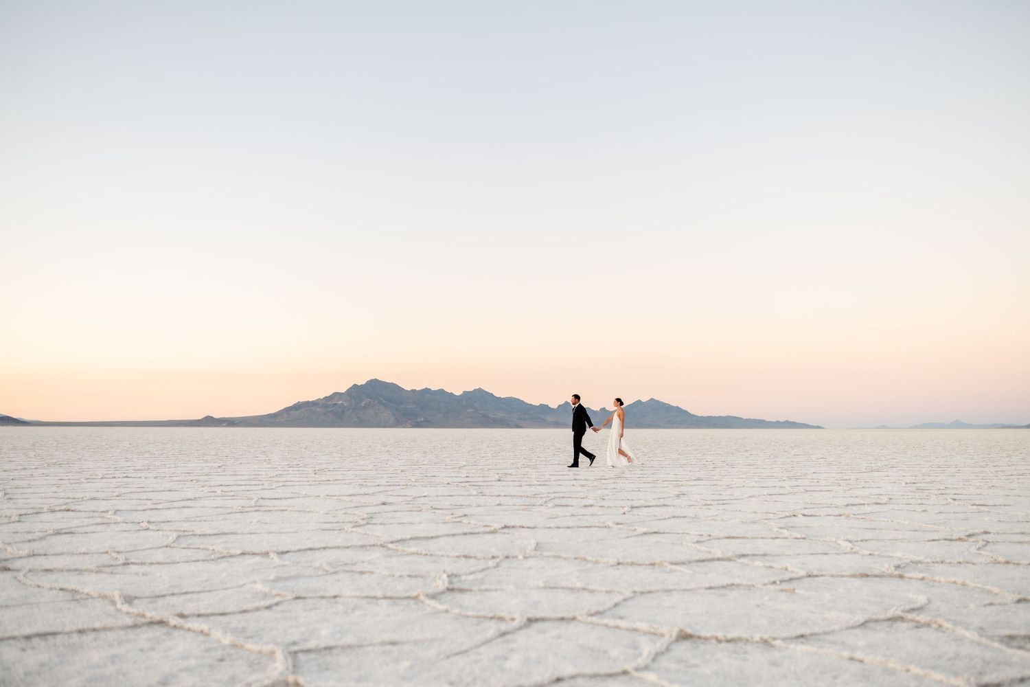 Utah Salt Flats Photographer. Silhouetted figures dancing on vast salt flats during golden hour.