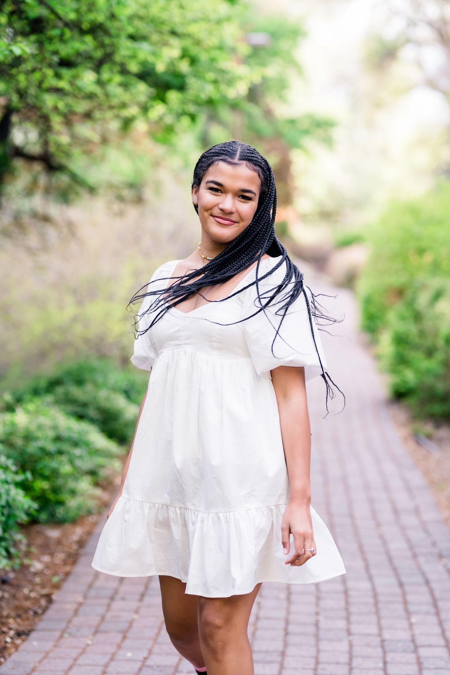 A series of outdoor portraits showing someone in a flowing white summer dress twirling and posing on a brick path.