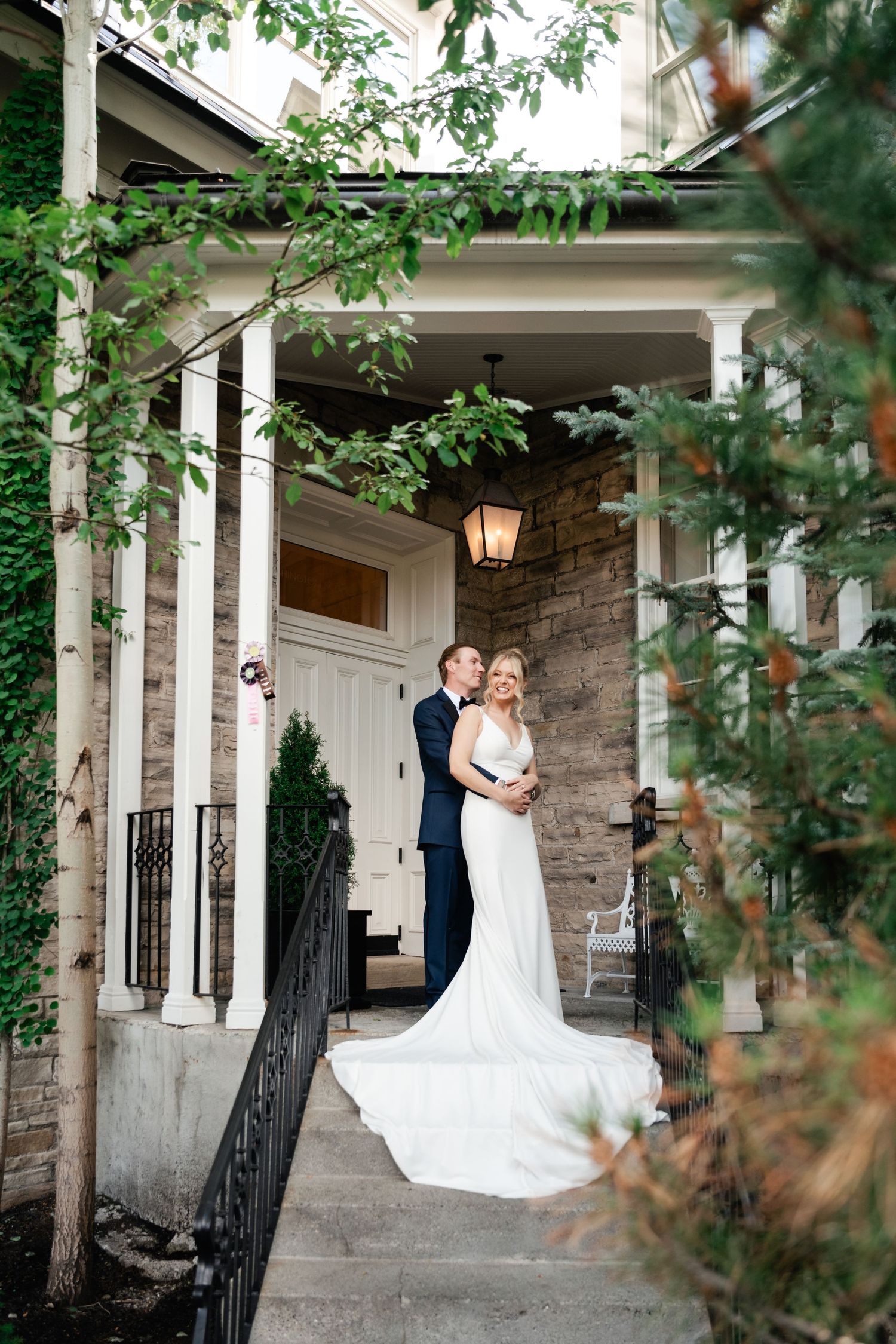 Bride and groom embrace on stone steps of elegant venue porch during their intimate Park City wedding at the Washington School House Hotel.