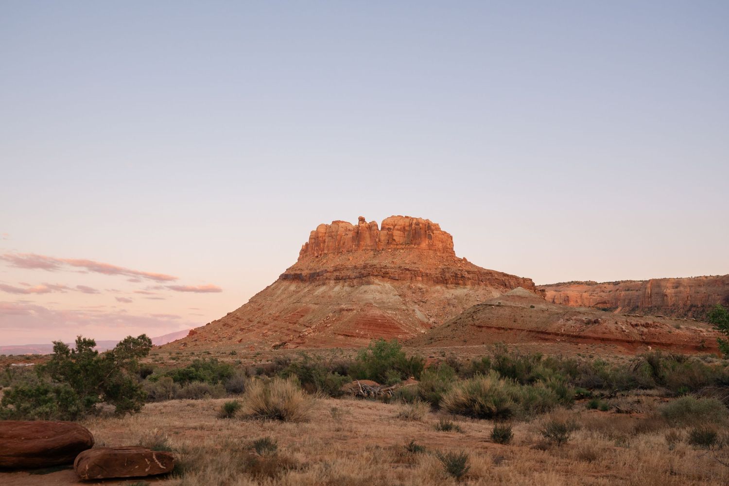 A stunning red rock butte glows at sunset in Moab, UT near Arches National Park.