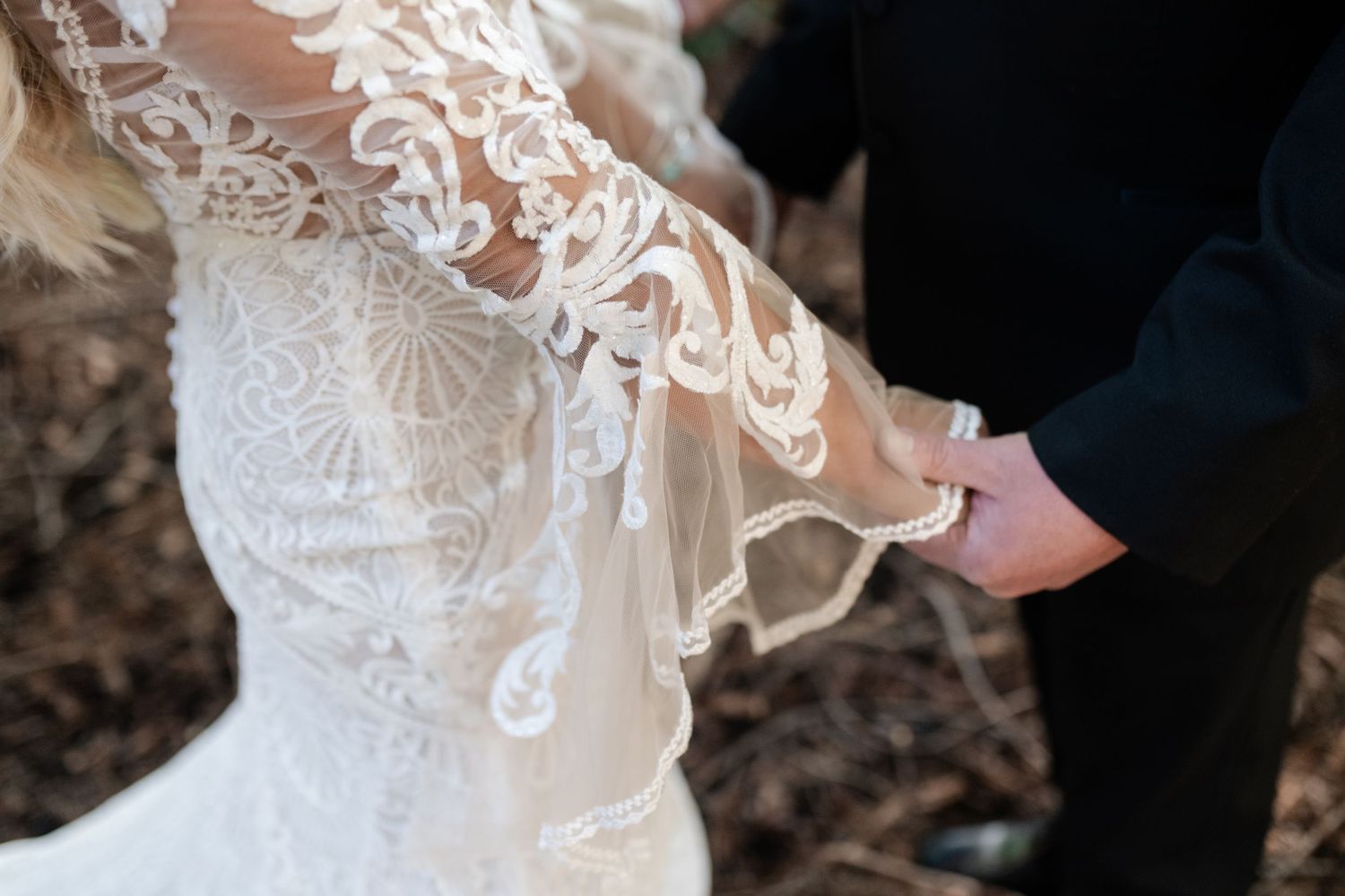 Close-up detail of delicate lace on a white wedding dress with intricate embroidery patterns.