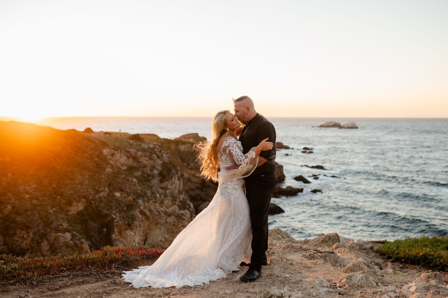 Romantic coastal wedding photos captured during golden hour on rocky cliffs.