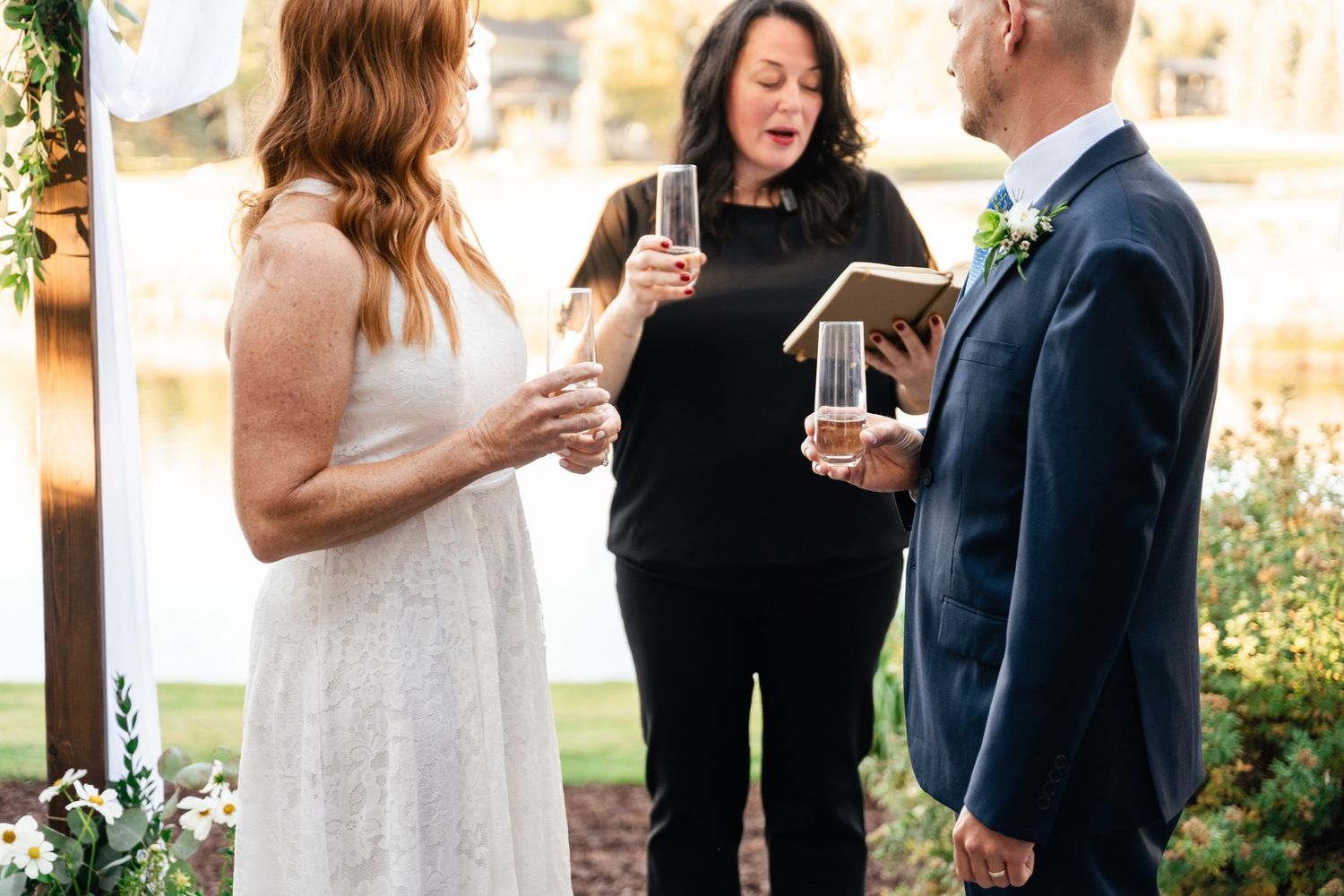 Outdoor wedding ceremony with guests mingling and holding drinks during a golden sunset.