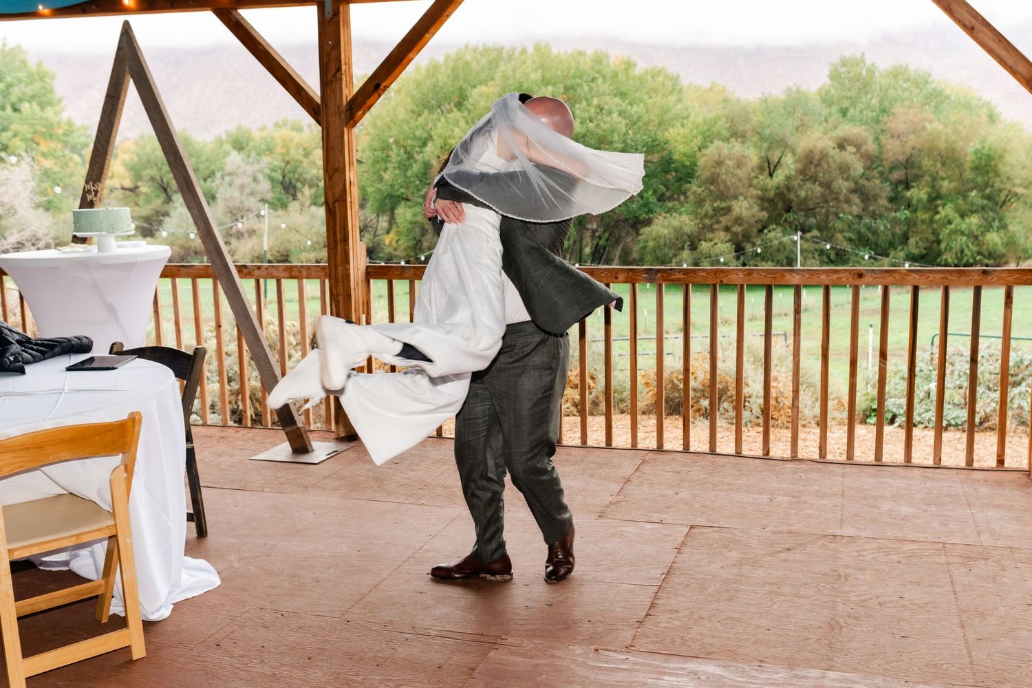 A celebratory dance moment on a covered wooden deck with mountain views.
