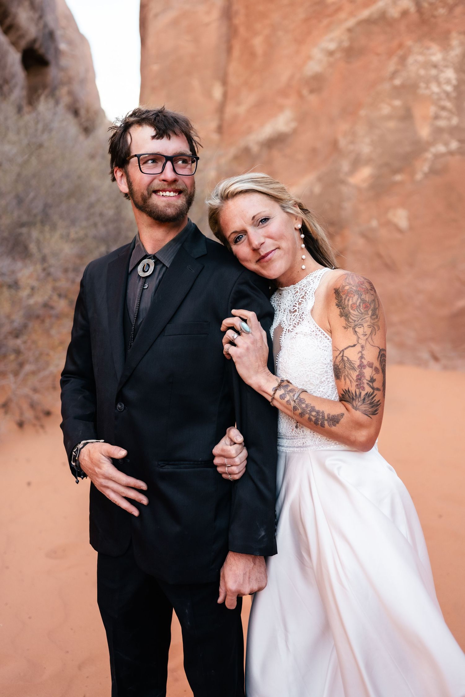 A couple shares intimate moments in front of red rock canyon walls during their desert wedding photoshoot.