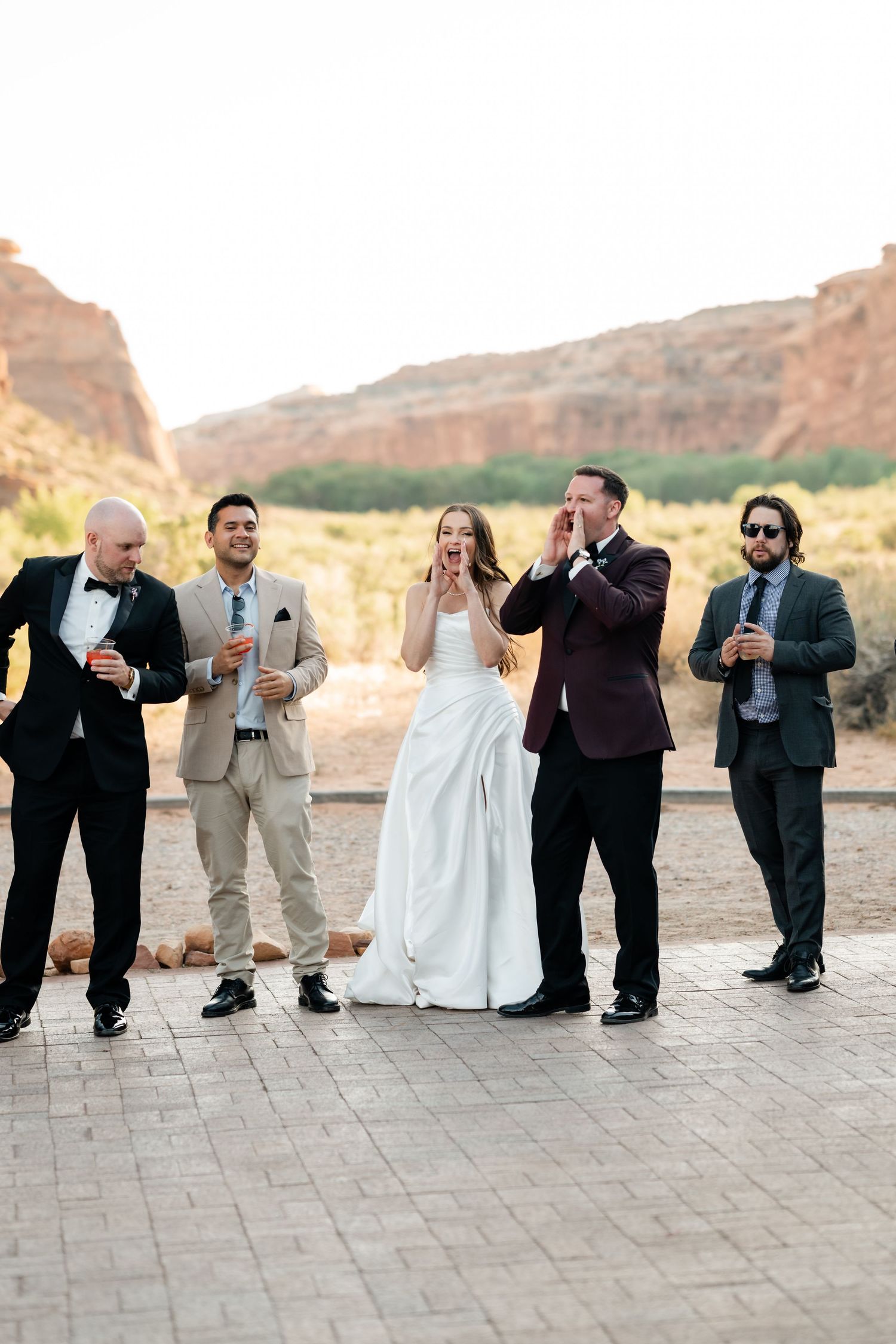 Bride and groom celebrating with wedding party guests against stunning red rock canyon backdrop.