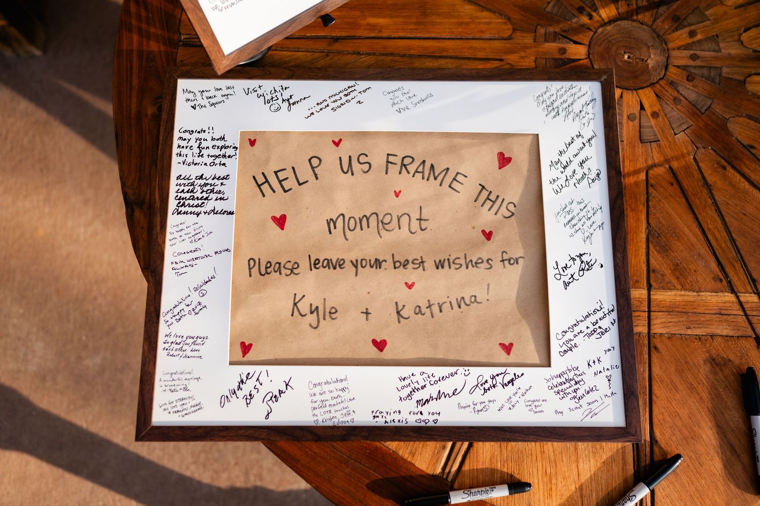 Guest book signing page with 'Help us frame a moment' message surrounded by handwritten signatures and hearts.