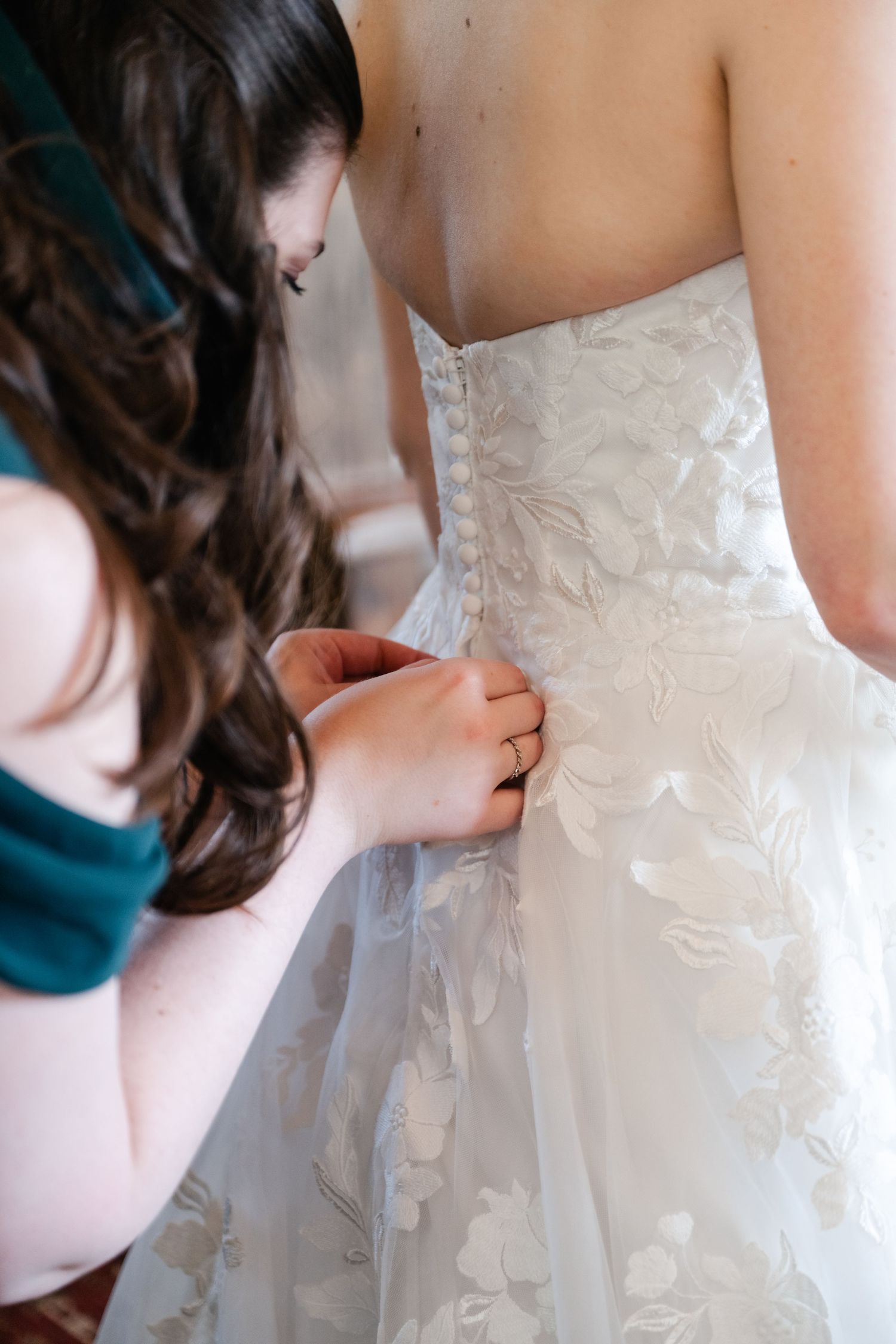 Close up details of delicate white lace and buttons on back of wedding dress.