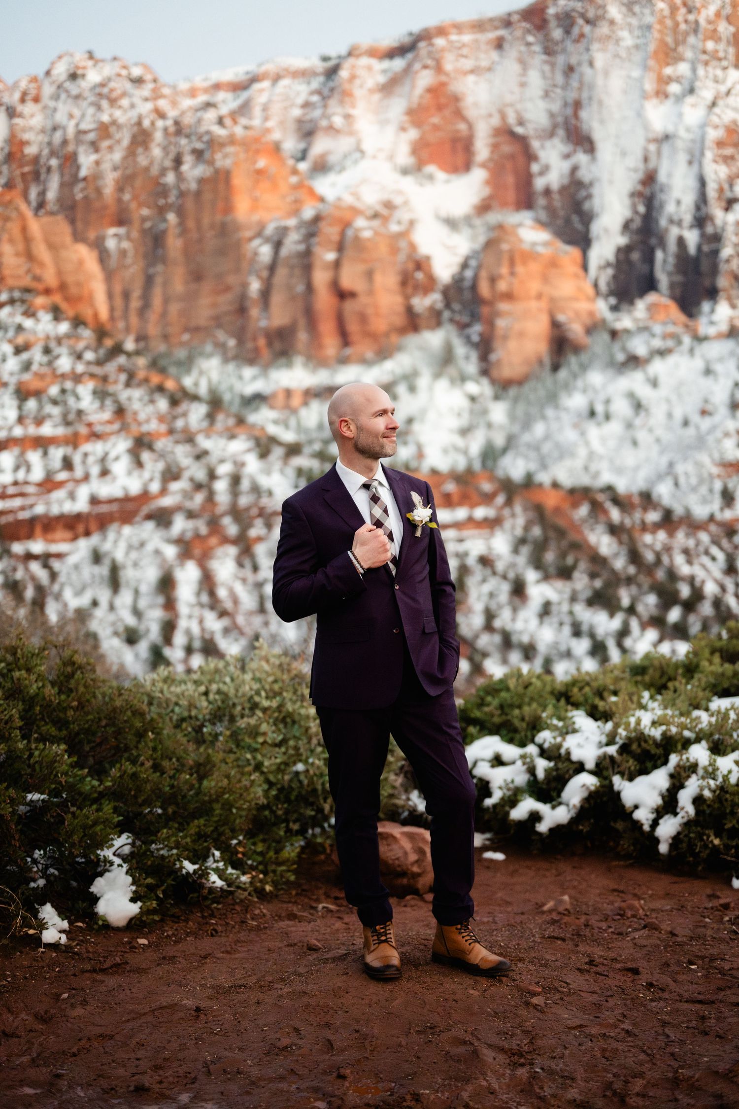 Wedding photography with snow-covered red rock cliffs and desert vegetation in background.