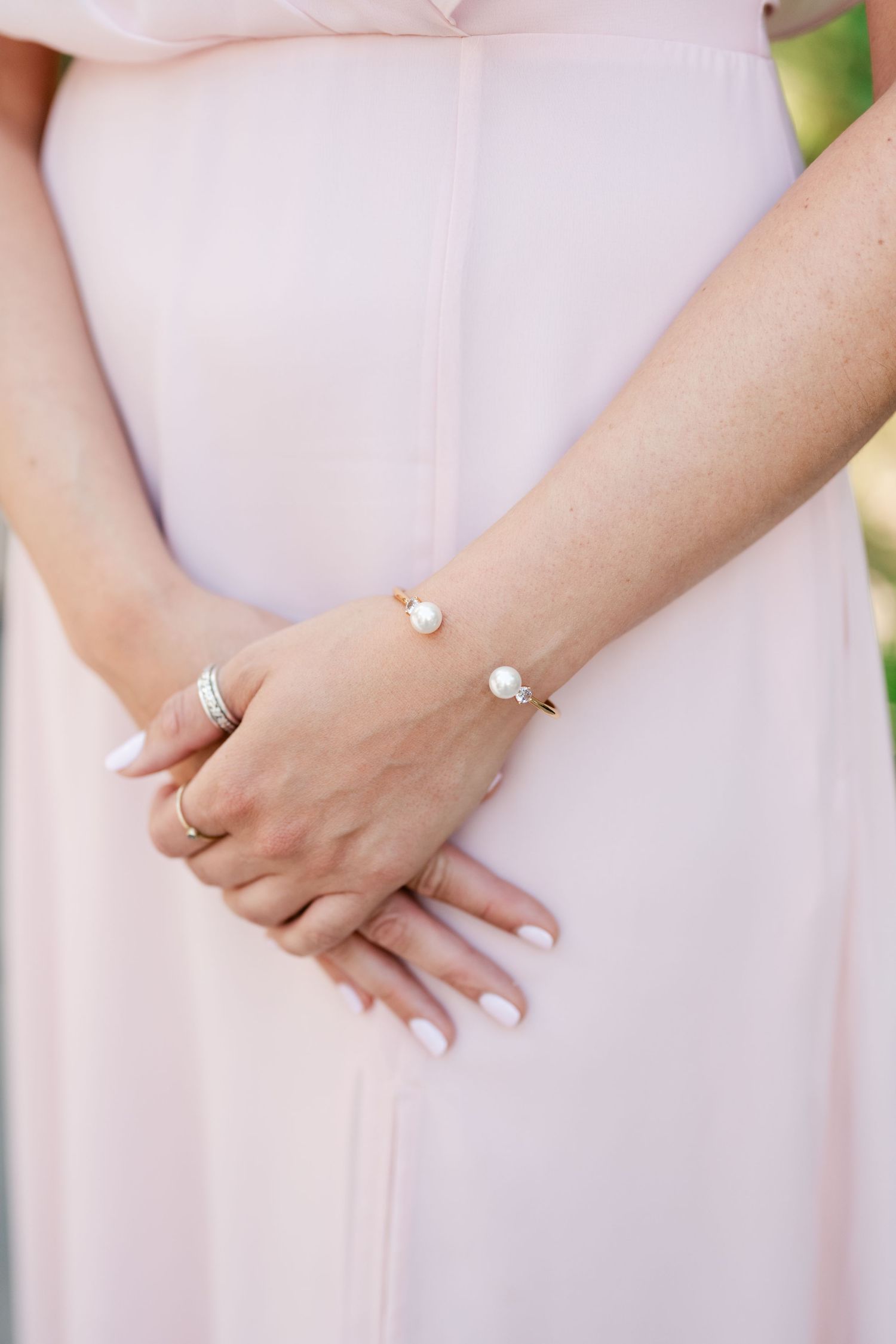 Close-up detail shots of elegant wedding rings and hands against a soft pink background.