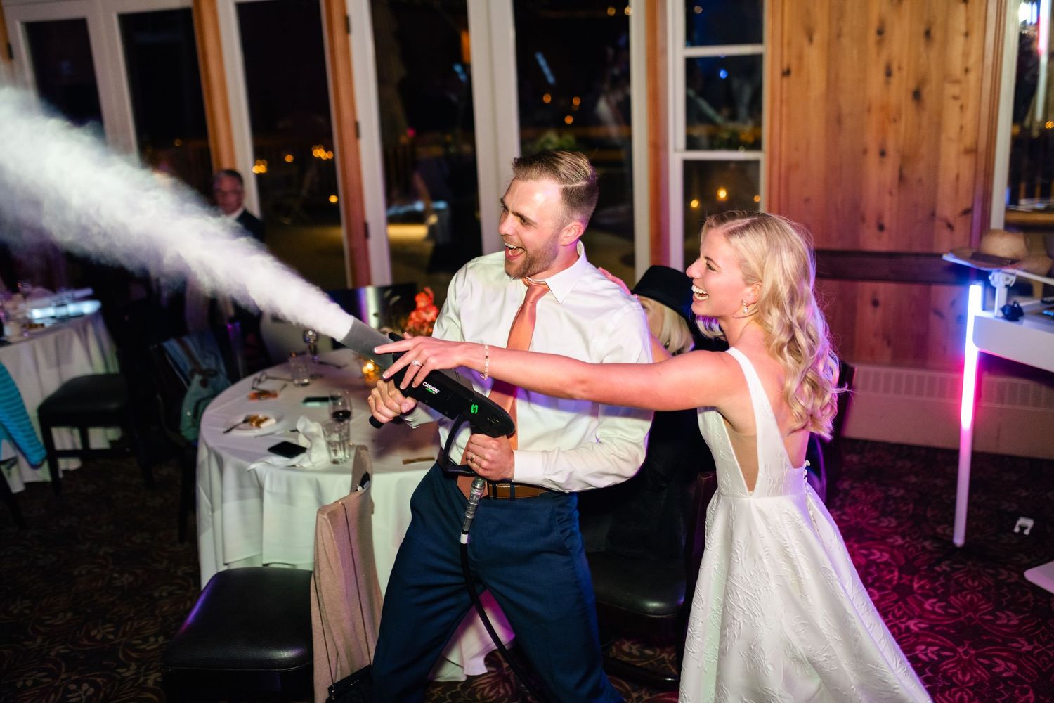 Wedding couple sprays CO2 cannons together while celebrating on the dance floor during their reception party. Utah Wedding Photographer.