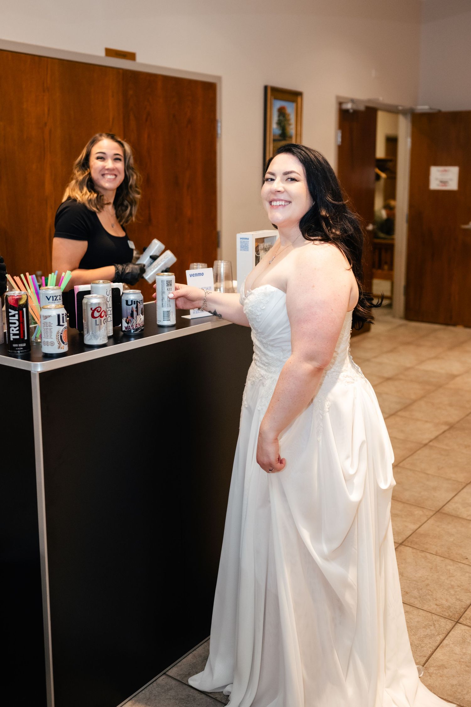 A bar setup at a wedding reception with drinks and bartender serving guests.