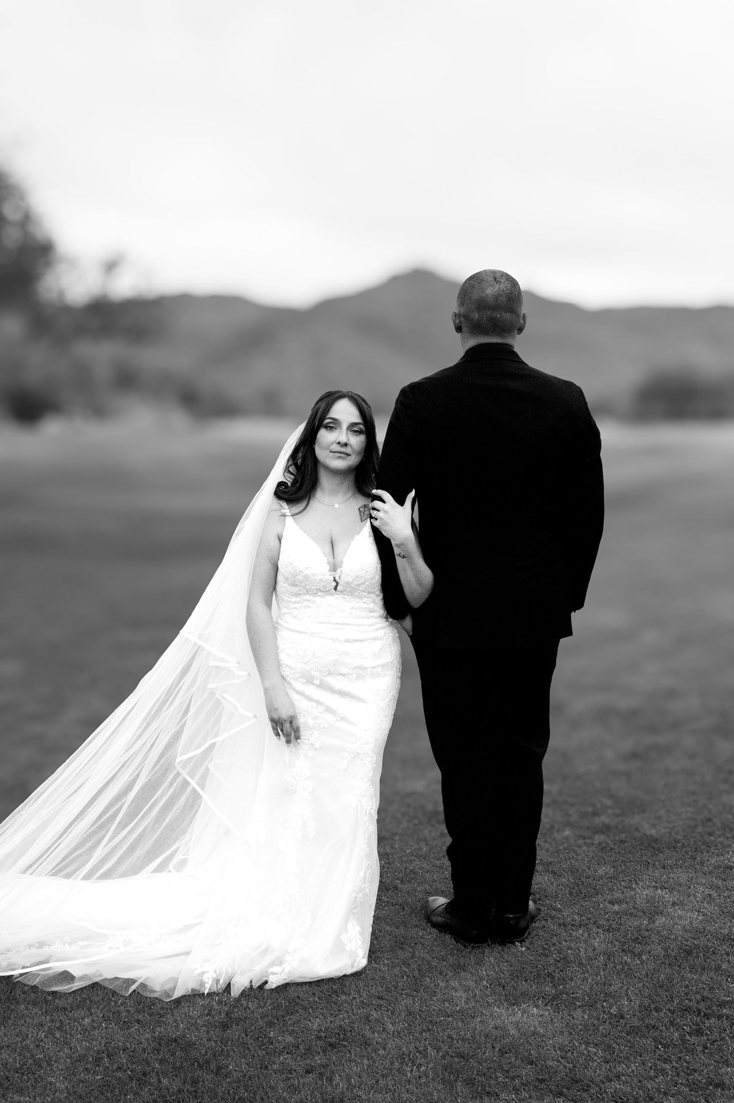 A black and white wedding photo sequence shows a bride and groom walking together across a grassy field.