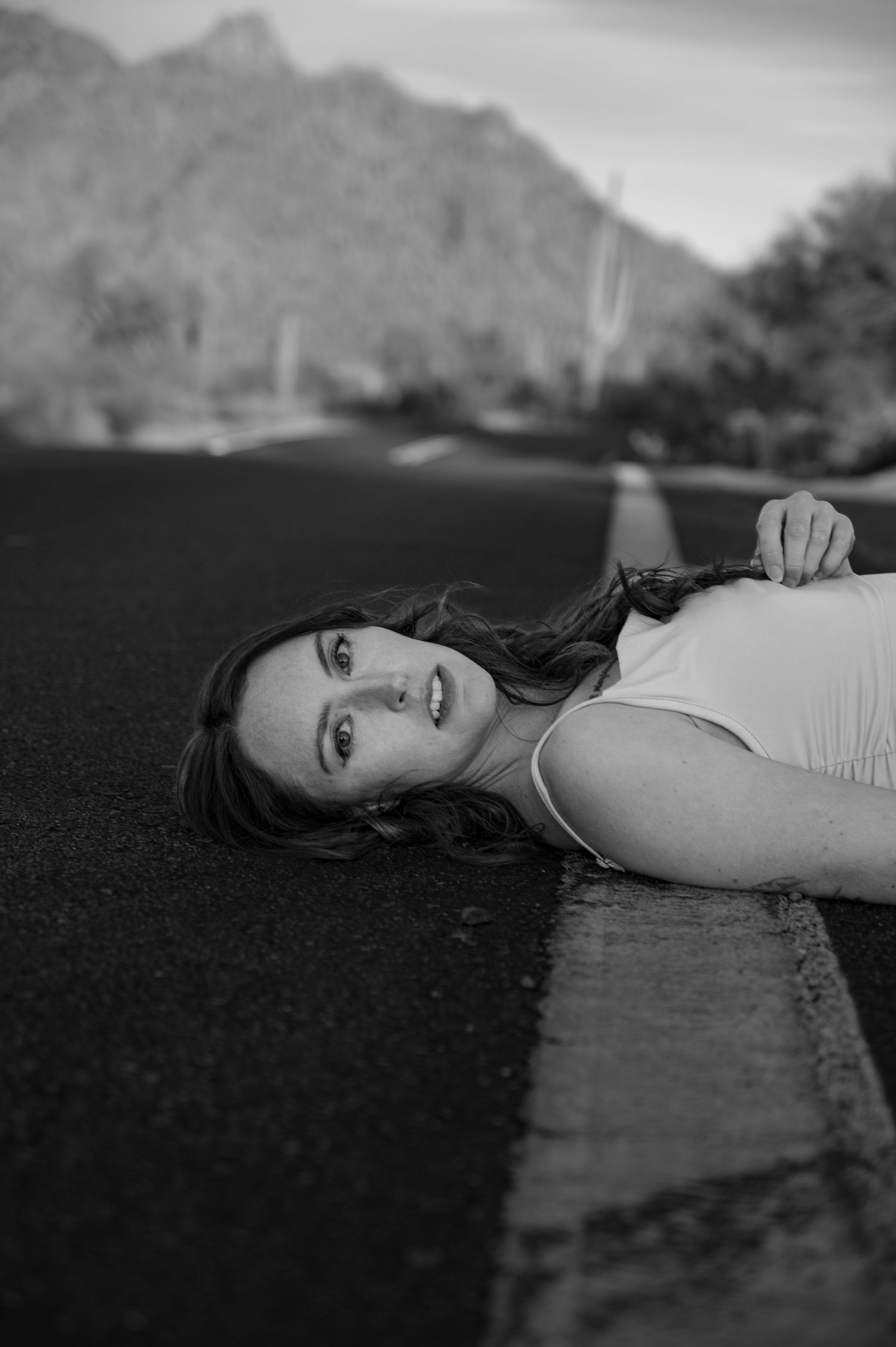 A series of black and white photographs showing someone lying on the ground with mountains visible in the background.