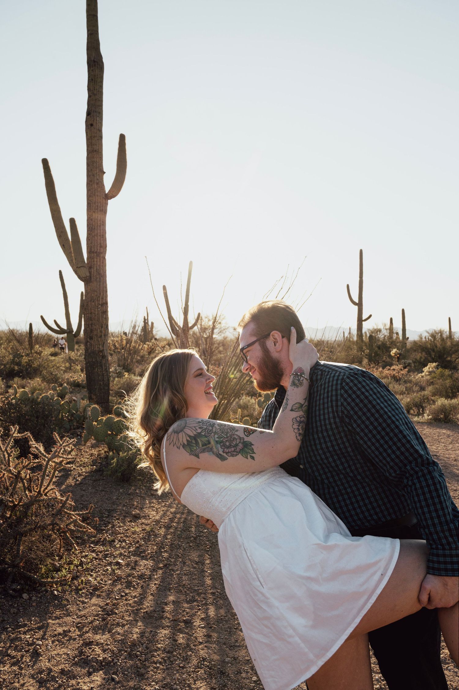 A couple dances and dips together in the Arizona desert with tall saguaro cacti at sunset.