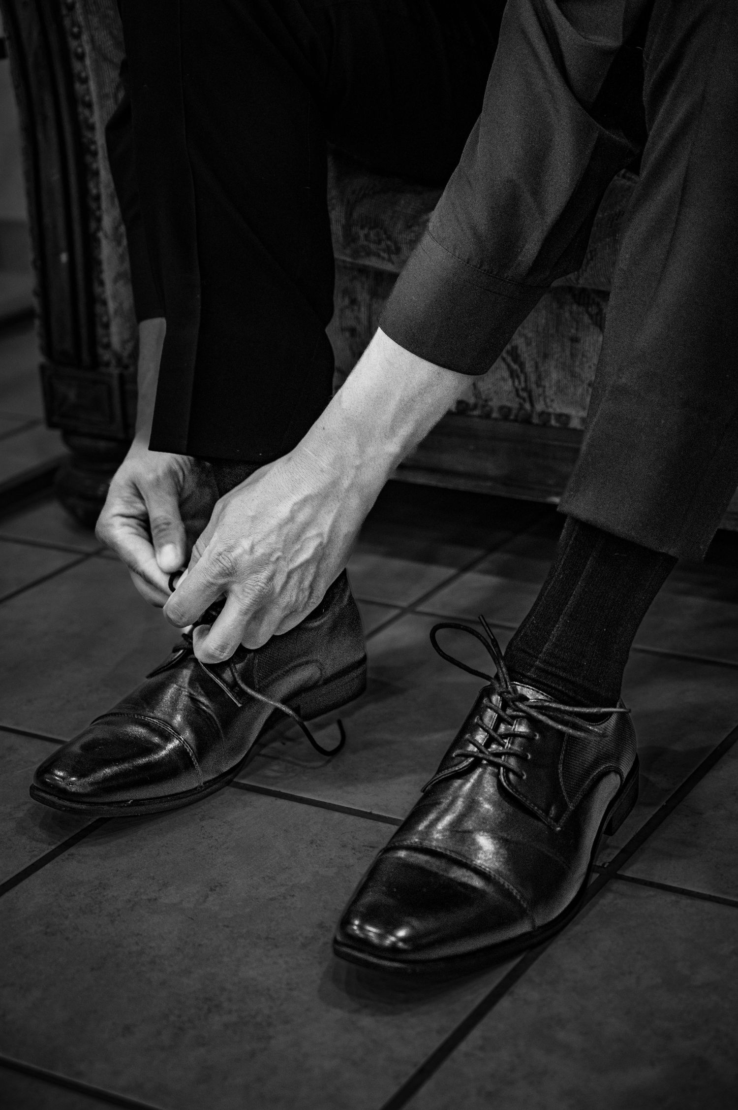 A series of black and white photos showing hands tying formal dress shoe laces in sequence.