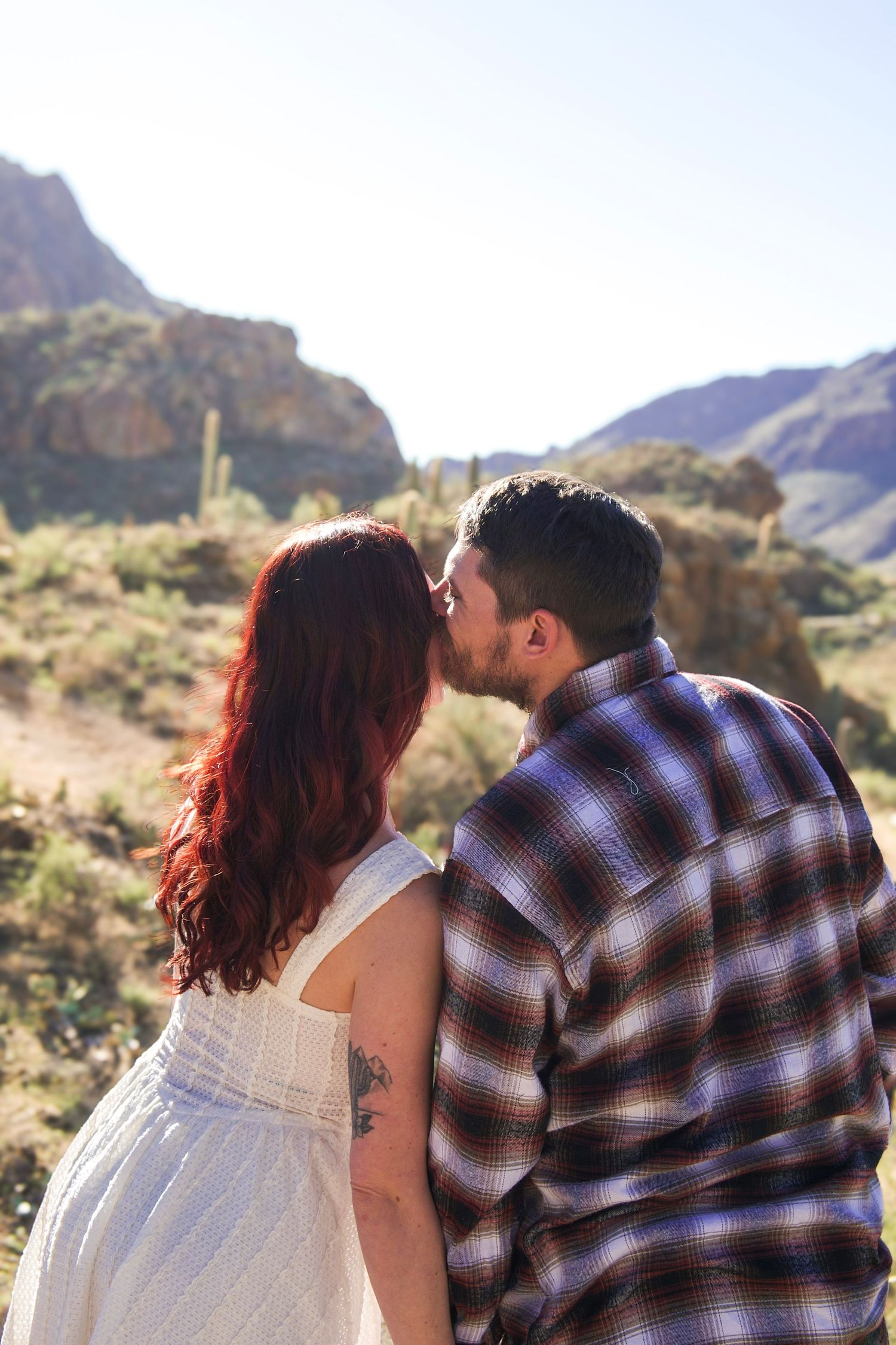 A romantic scene unfolds against a dramatic desert mountain backdrop with saguaro cacti.