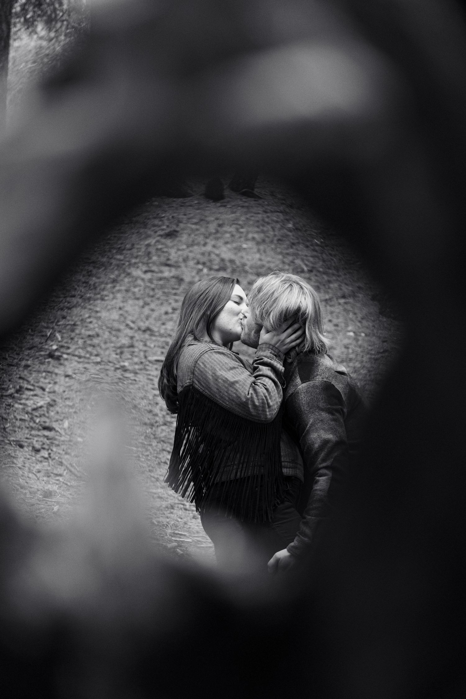 A black and white artistic photograph captures an intimate moment between two people.