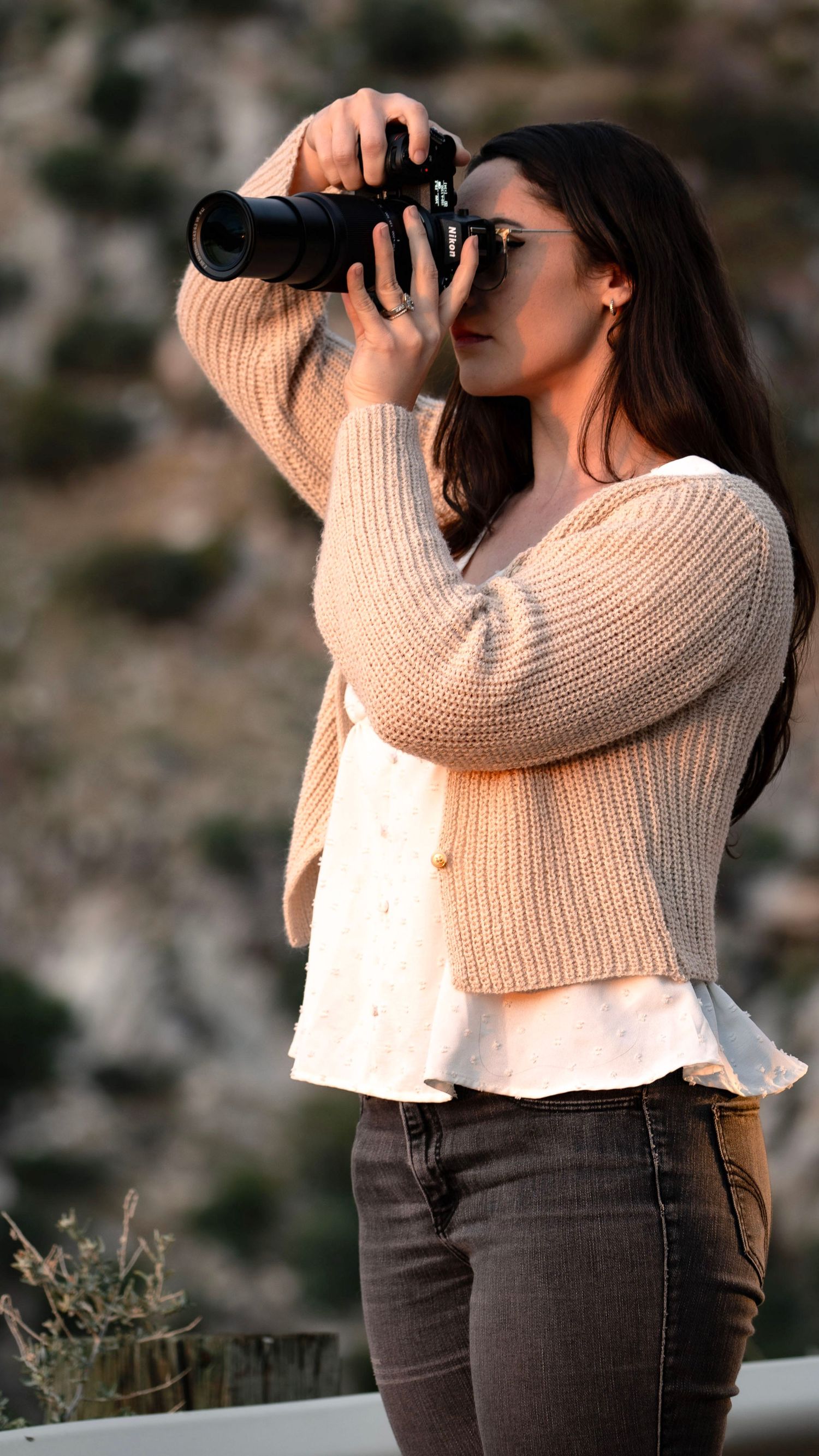 A photographer takes photos with a professional camera during golden hour in an outdoor setting.