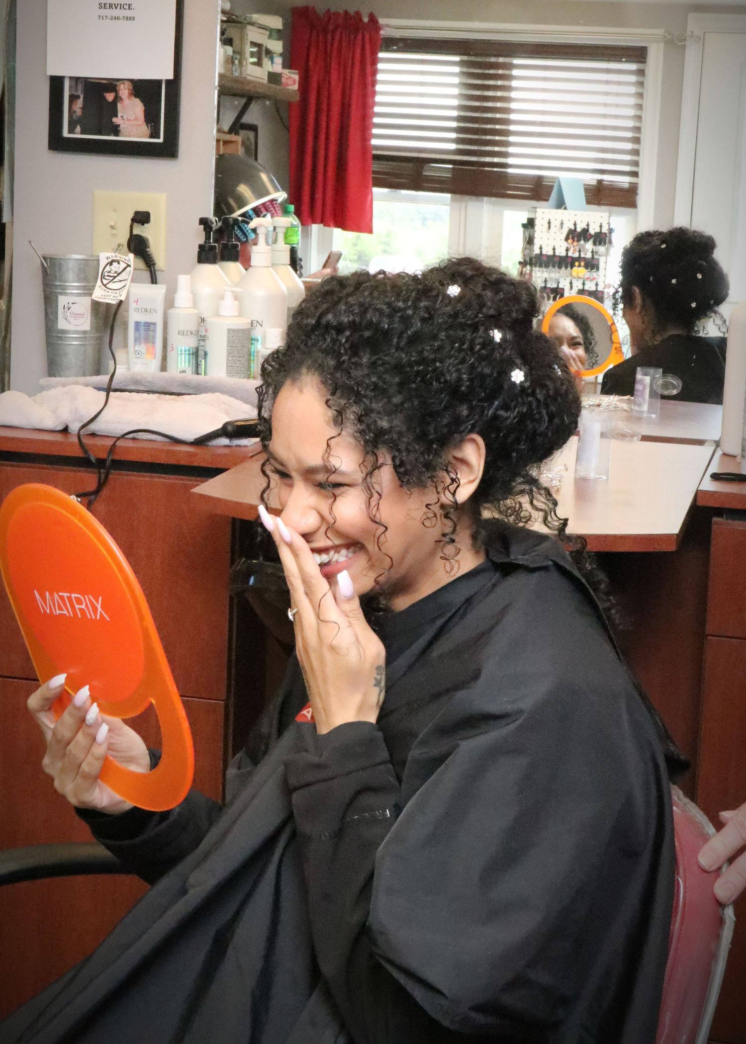 Client admiring their new hairstyle while holding a mirror in a salon setting.