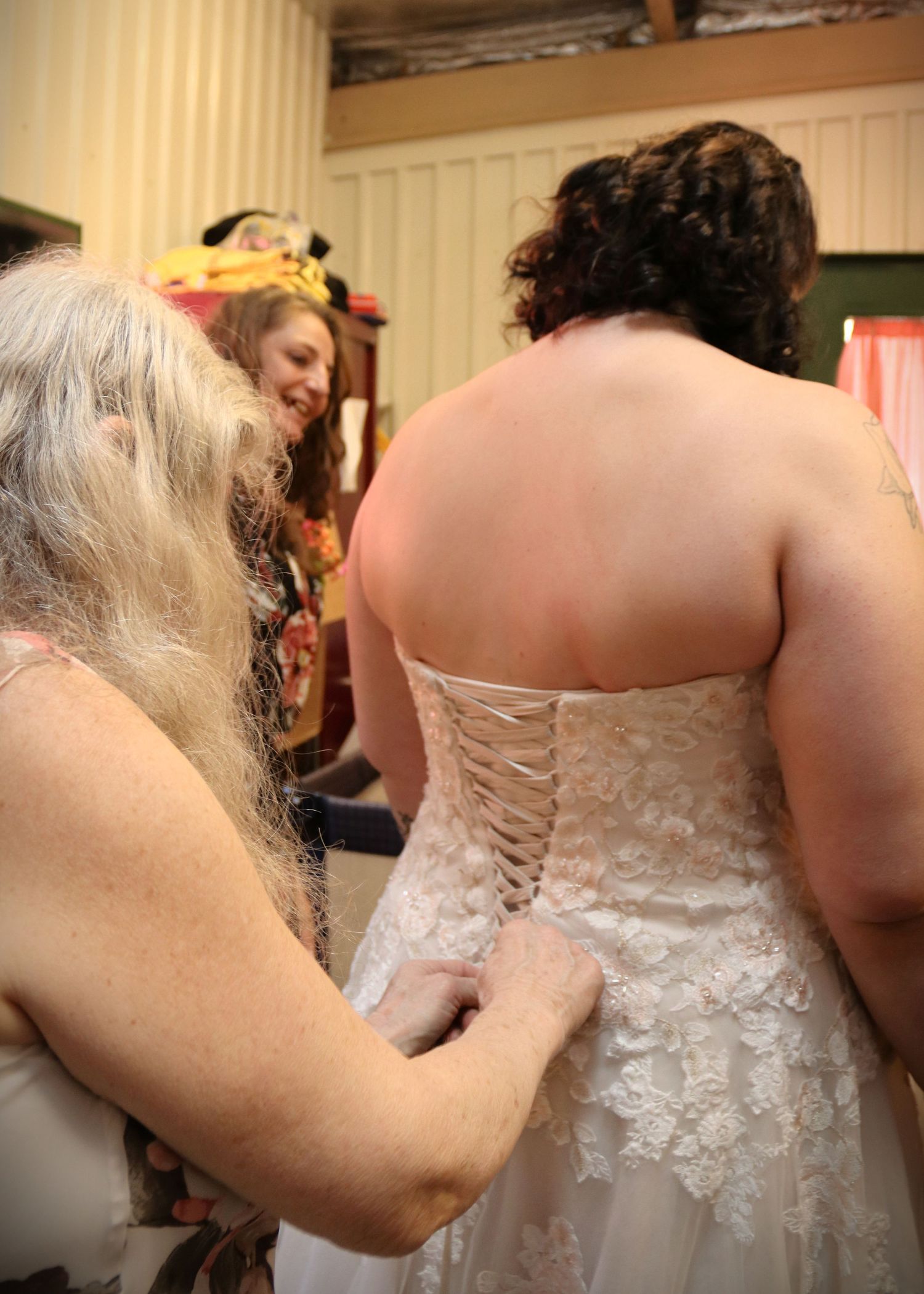 Back view of wedding dress being laced up by someone with long hair.