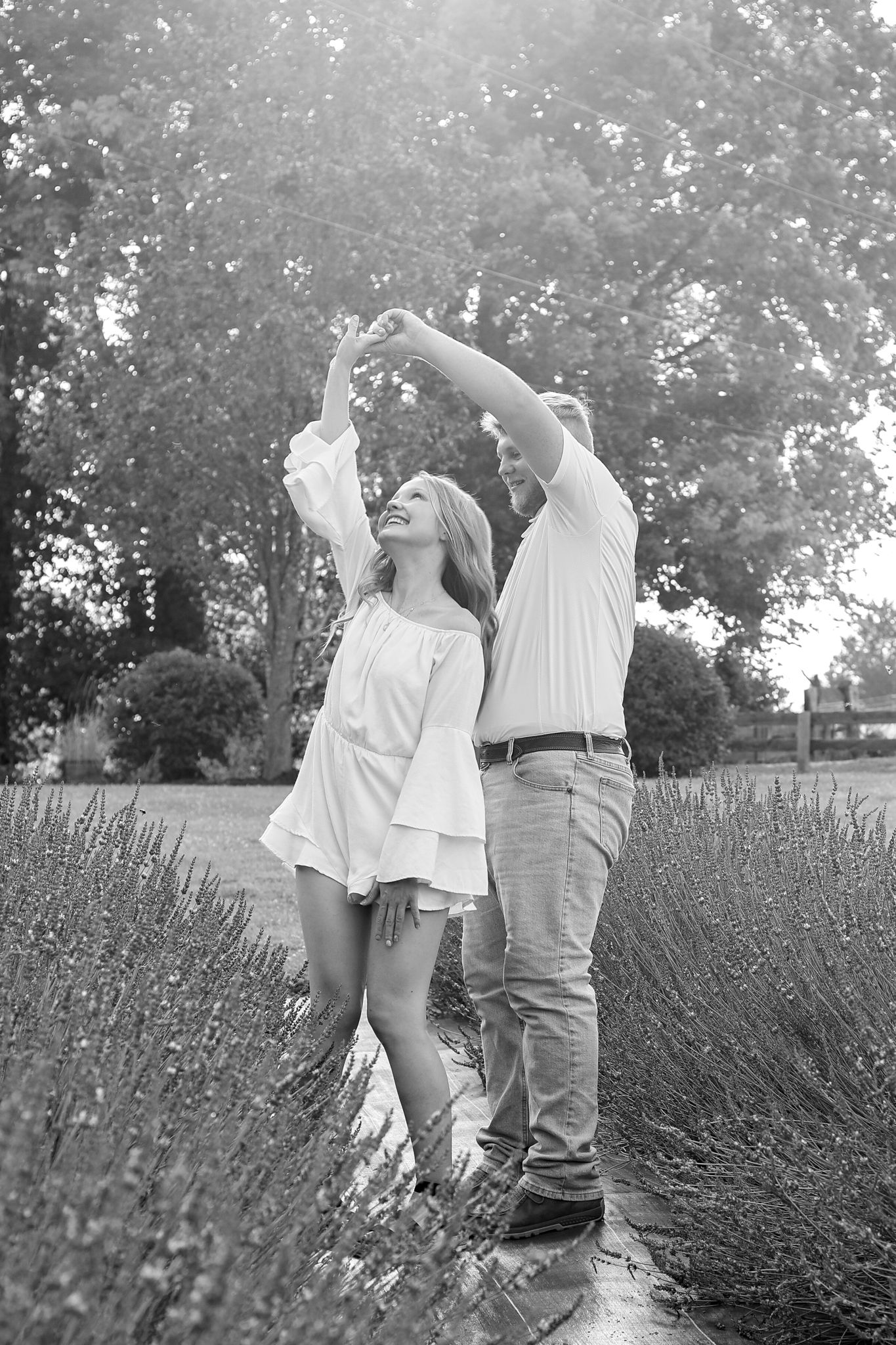 Dancing couple in white clothing among lavender plants in black and white photography.