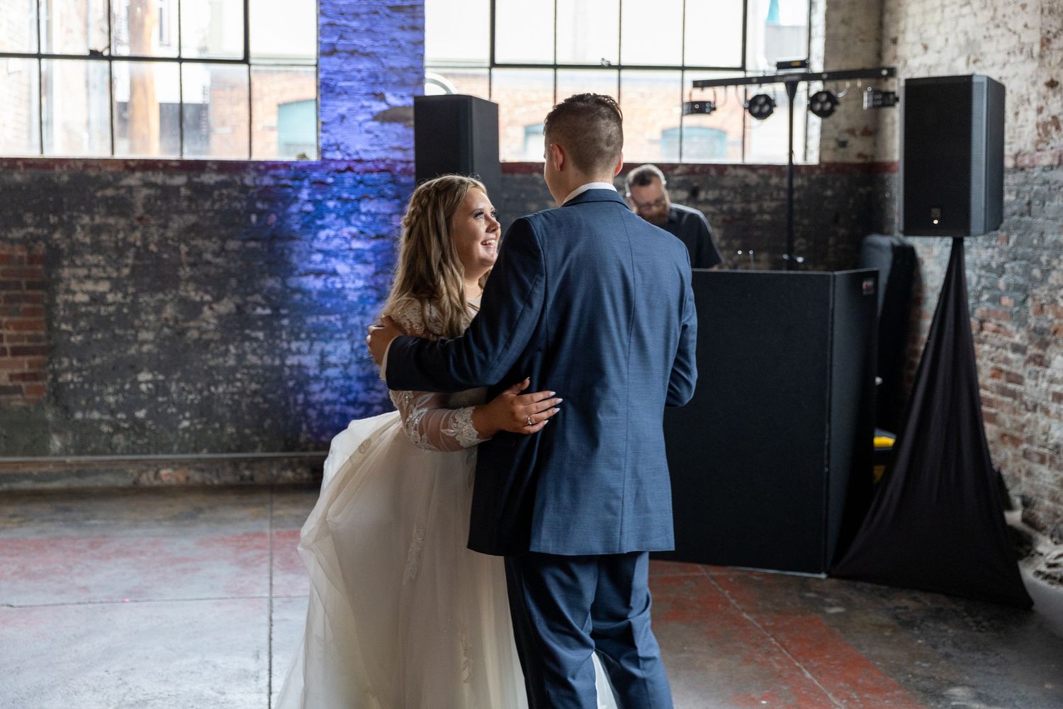 A couple dances together in an industrial-style venue during their wedding reception.
