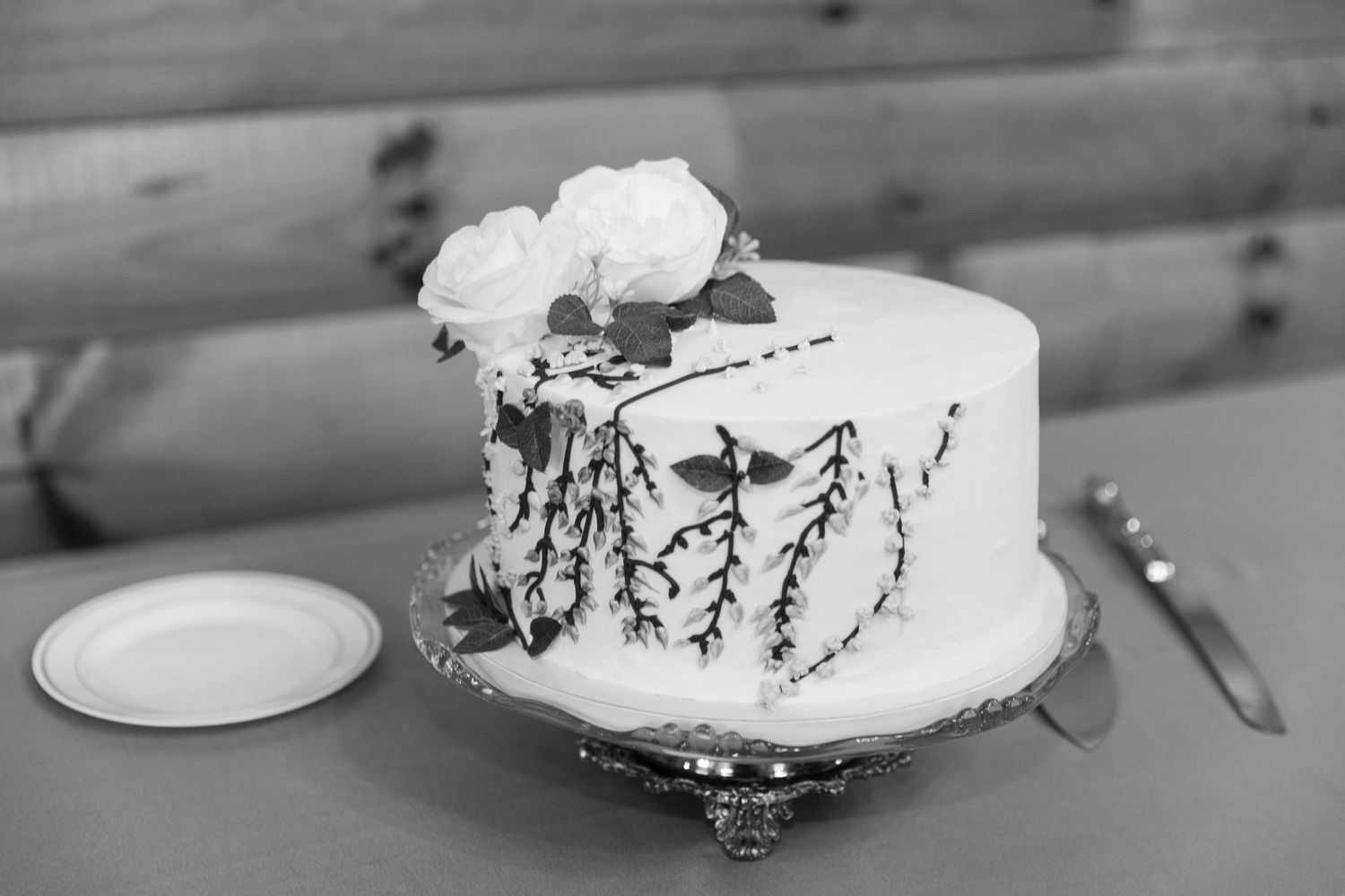 Simple white wedding cake with floral decoration and delicate branch design in black and white.