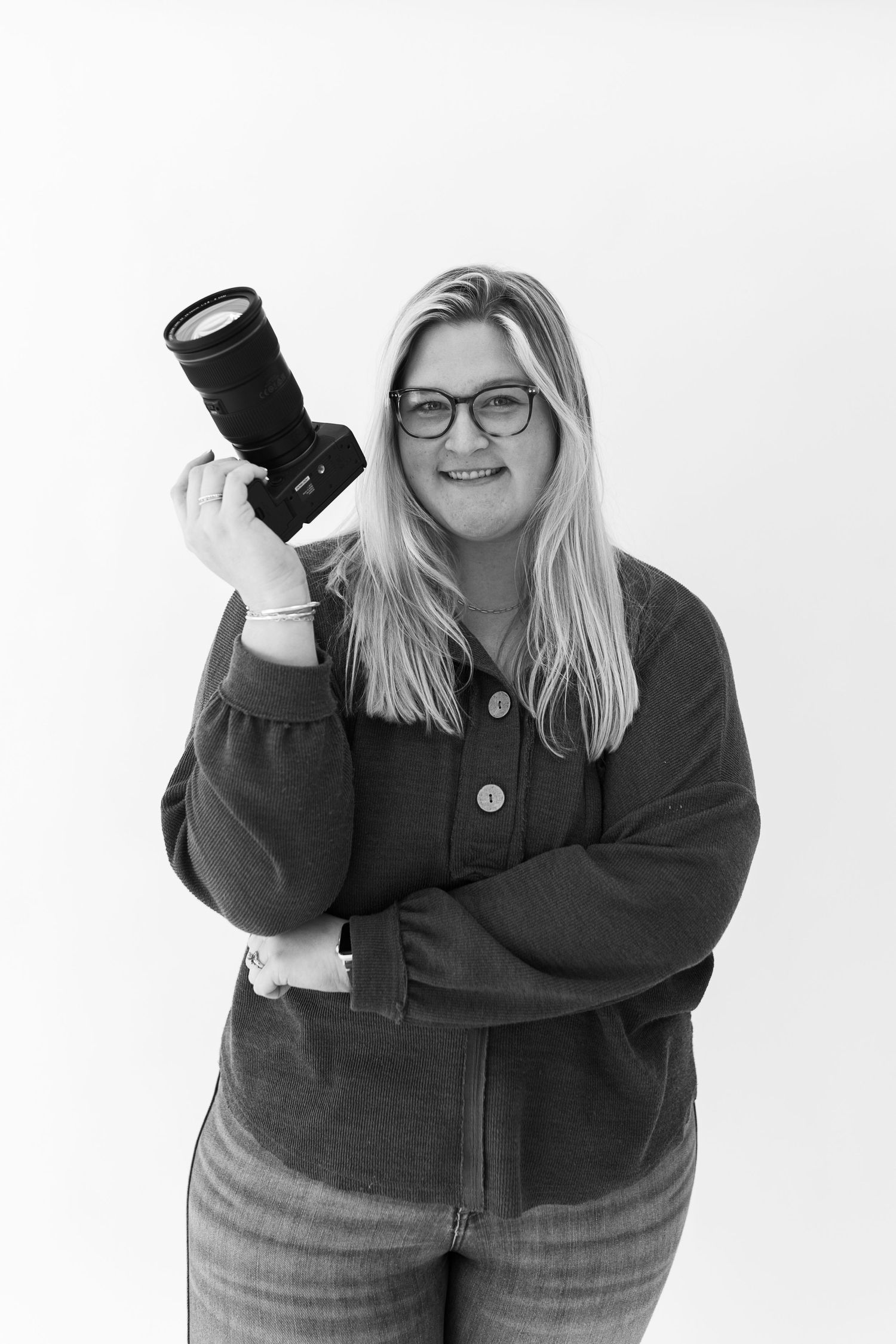 Professional photographer holding camera lens against white background.