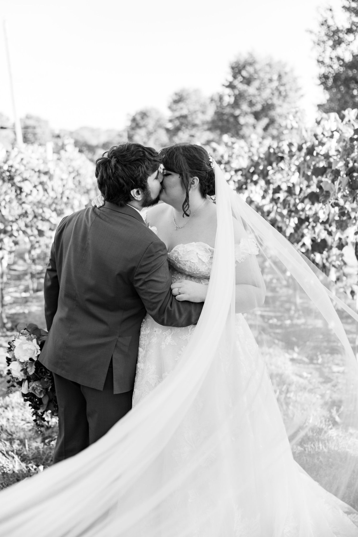 A black and white wedding photo capturing an intimate moment with flowing veil details.