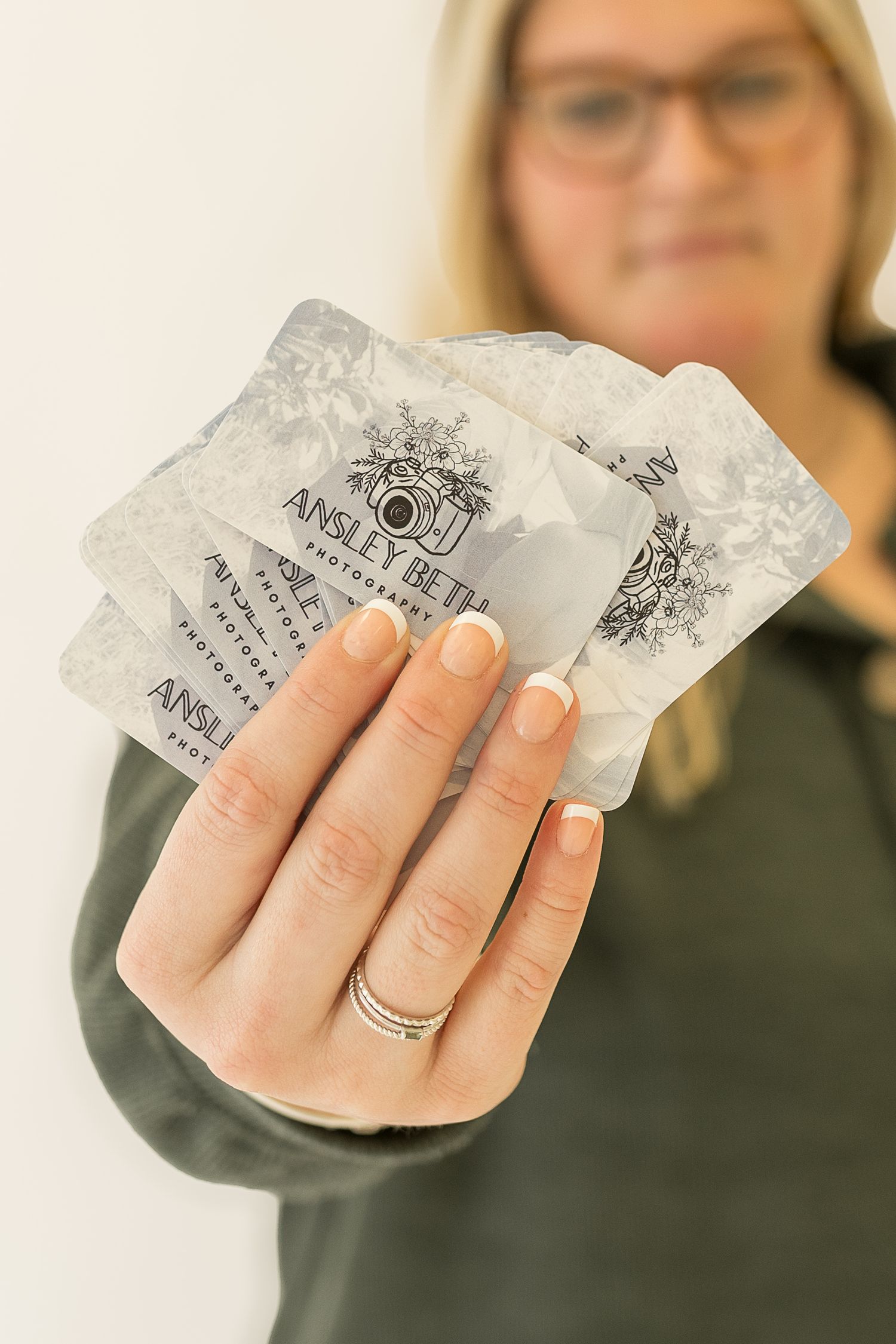 Hand holding business cards showing photography branding and logo design.