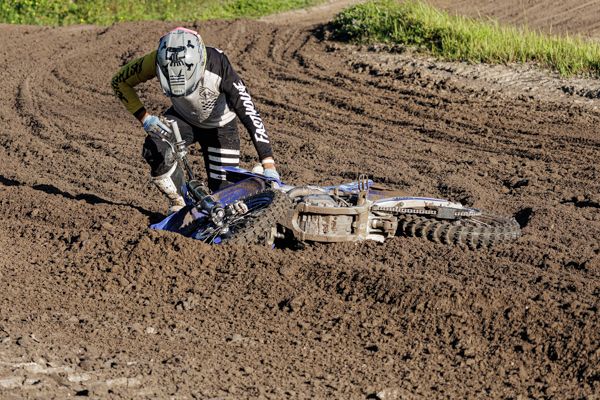 A dirt bike rider navigates through a muddy motocross track during an off-road racing competition.