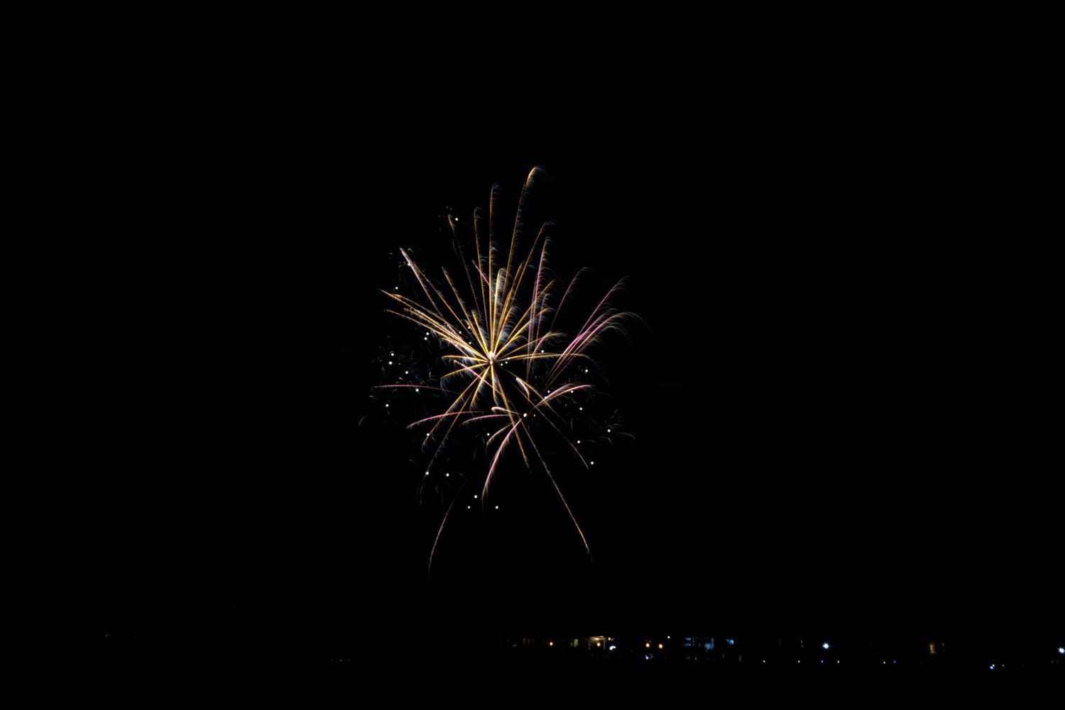 A sequence of firework bursts against a dark night sky creating bright white starlike patterns.