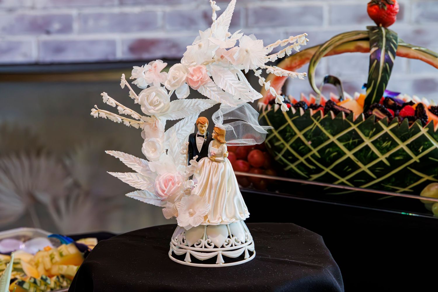 Elegant wedding reception table setting with white floral centerpieces and crystal glassware on a dark tablecloth.