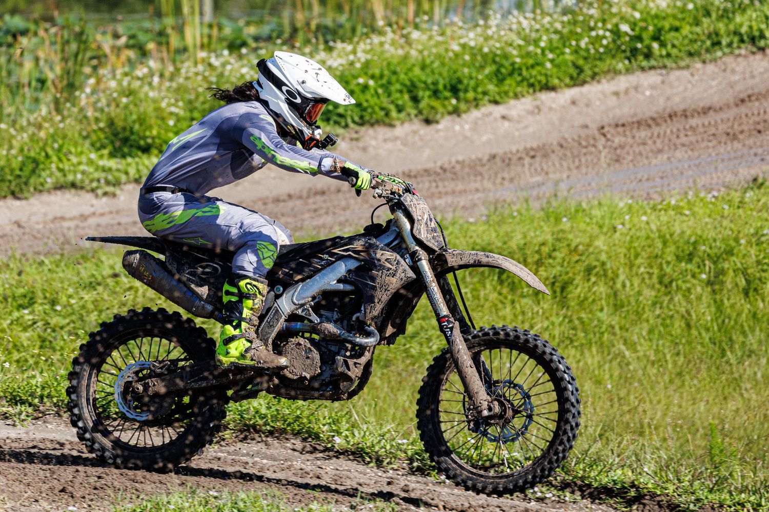 Motocross rider navigates a dirt track corner with precise control and technique during an off-road race.