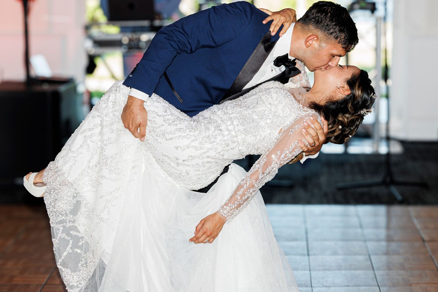 A couple performs a romantic dip during their first dance at a wedding reception.