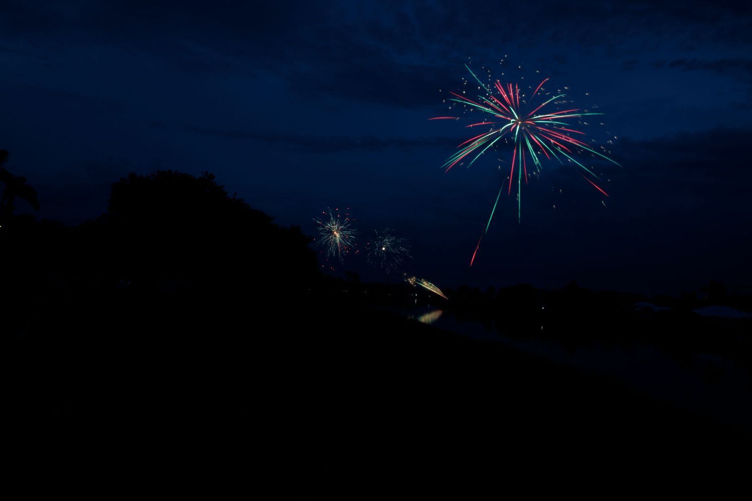 Bright colorful fireworks explode against a dark night sky, creating a spectacular display of light and color.