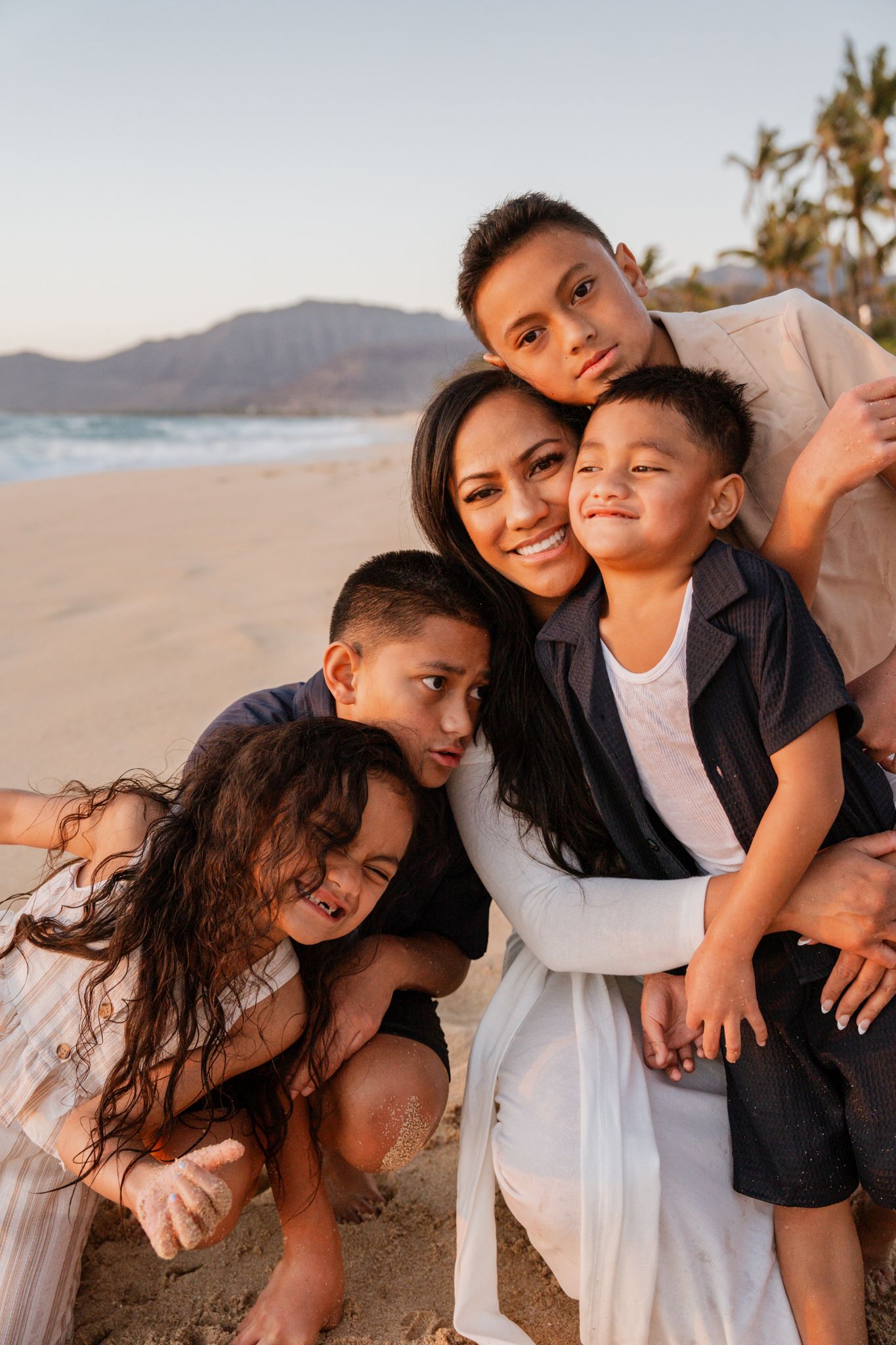 A family poses together for a portrait on the beach at golden hour.