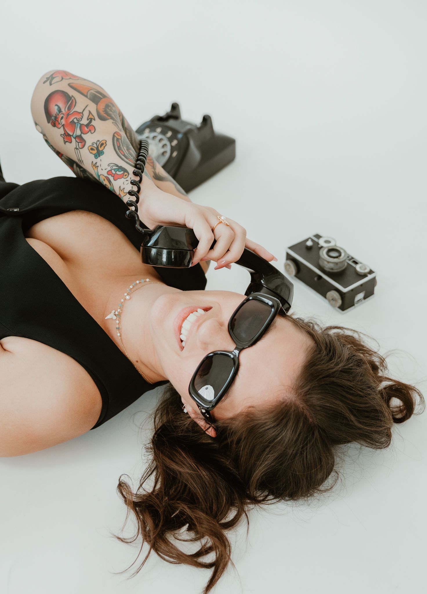 Creative portrait of photographer lying down with vintage cameras and sunglasses.