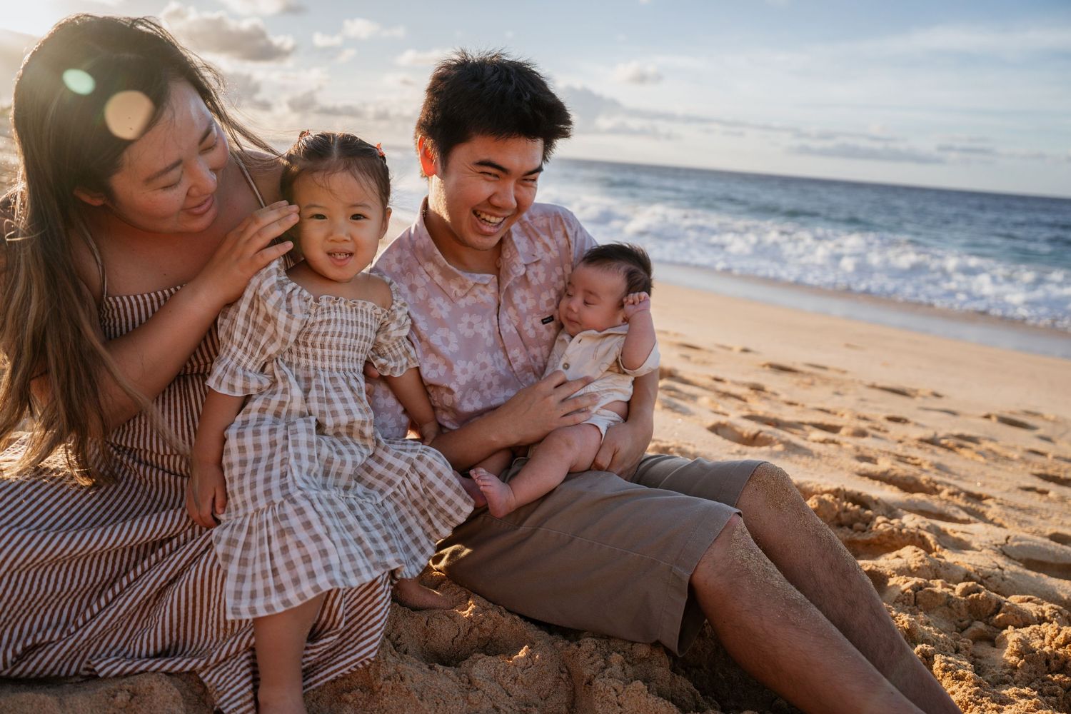 A loving family enjoys a tender moment together on a sandy beach during golden hour. Honolulu Photographer sunrise