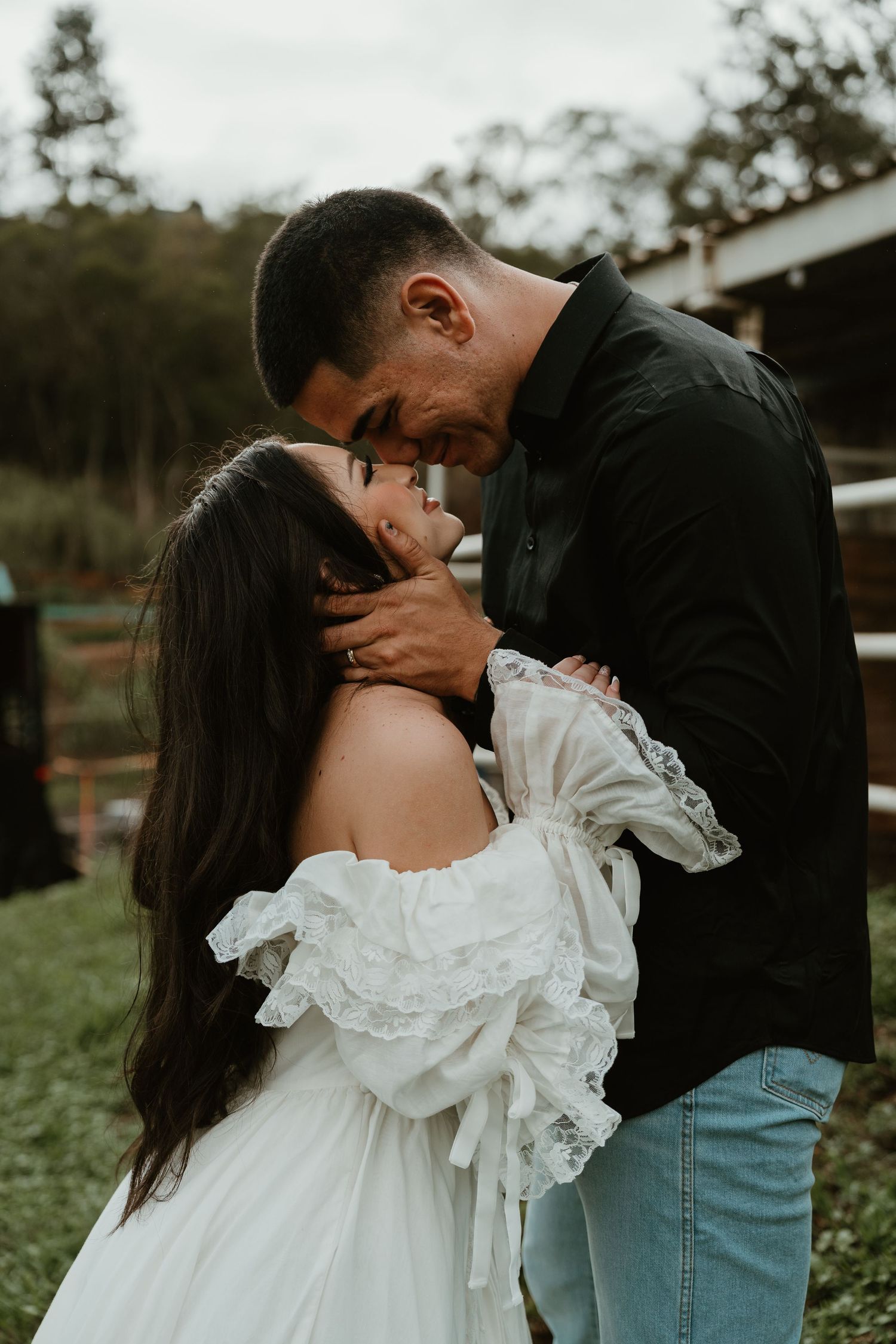 A romantic outdoor portrait shows a couple in an intimate embrace, with the woman wearing a flowing white dress.