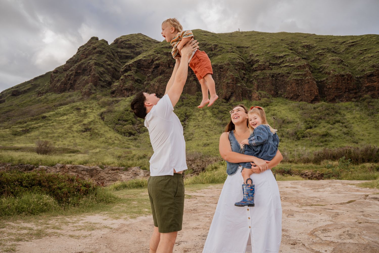 Family sharing joyful moments against stunning Hawaiian mountain landscape.